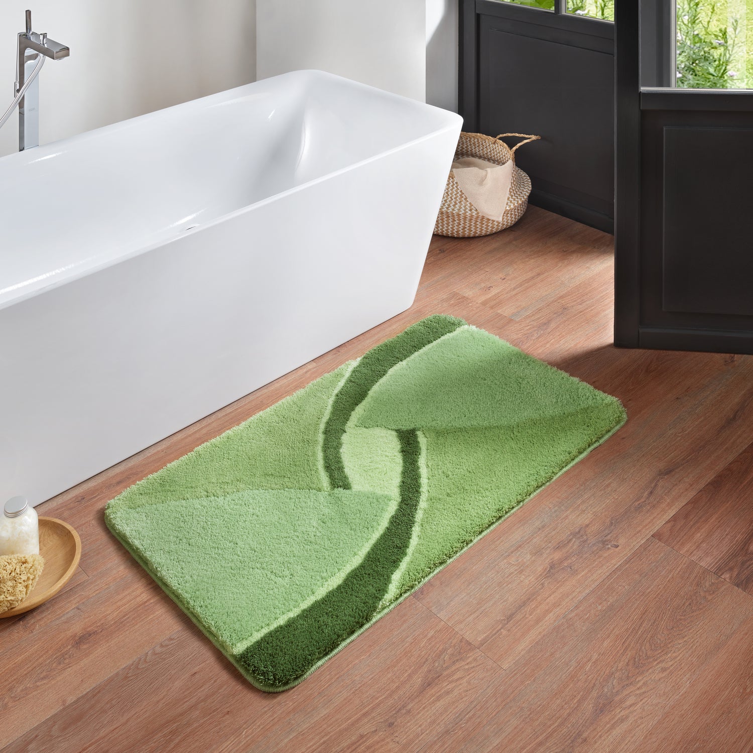 Grüner Badteppich Kleine Wolke Creativo Centro liegt vor weißer Badewanne auf Holzfußboden.