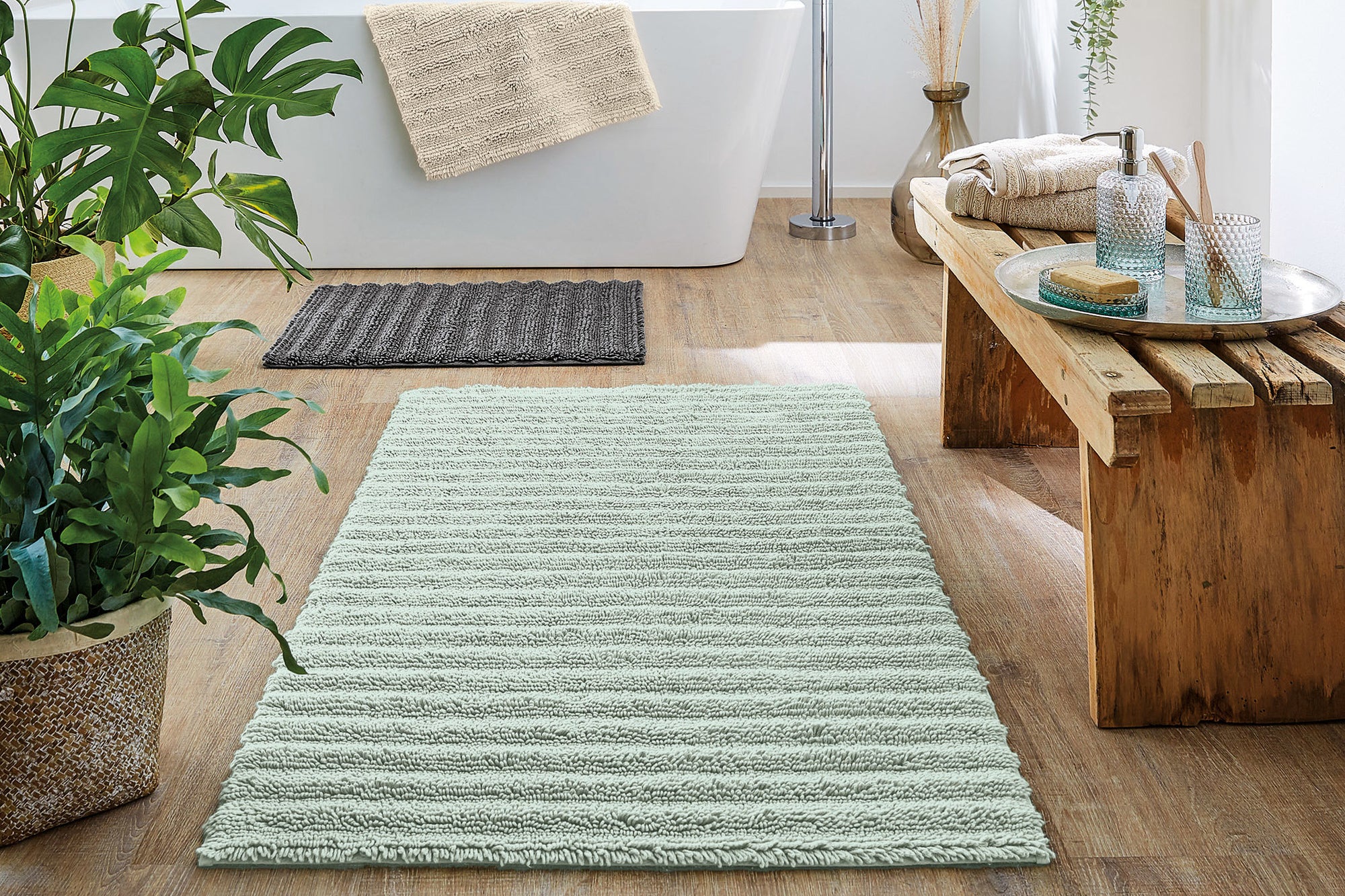 Bad mit grüner Kleine Wolke Eco Collection Badematte, Holzmöbeln und Pflanzen.