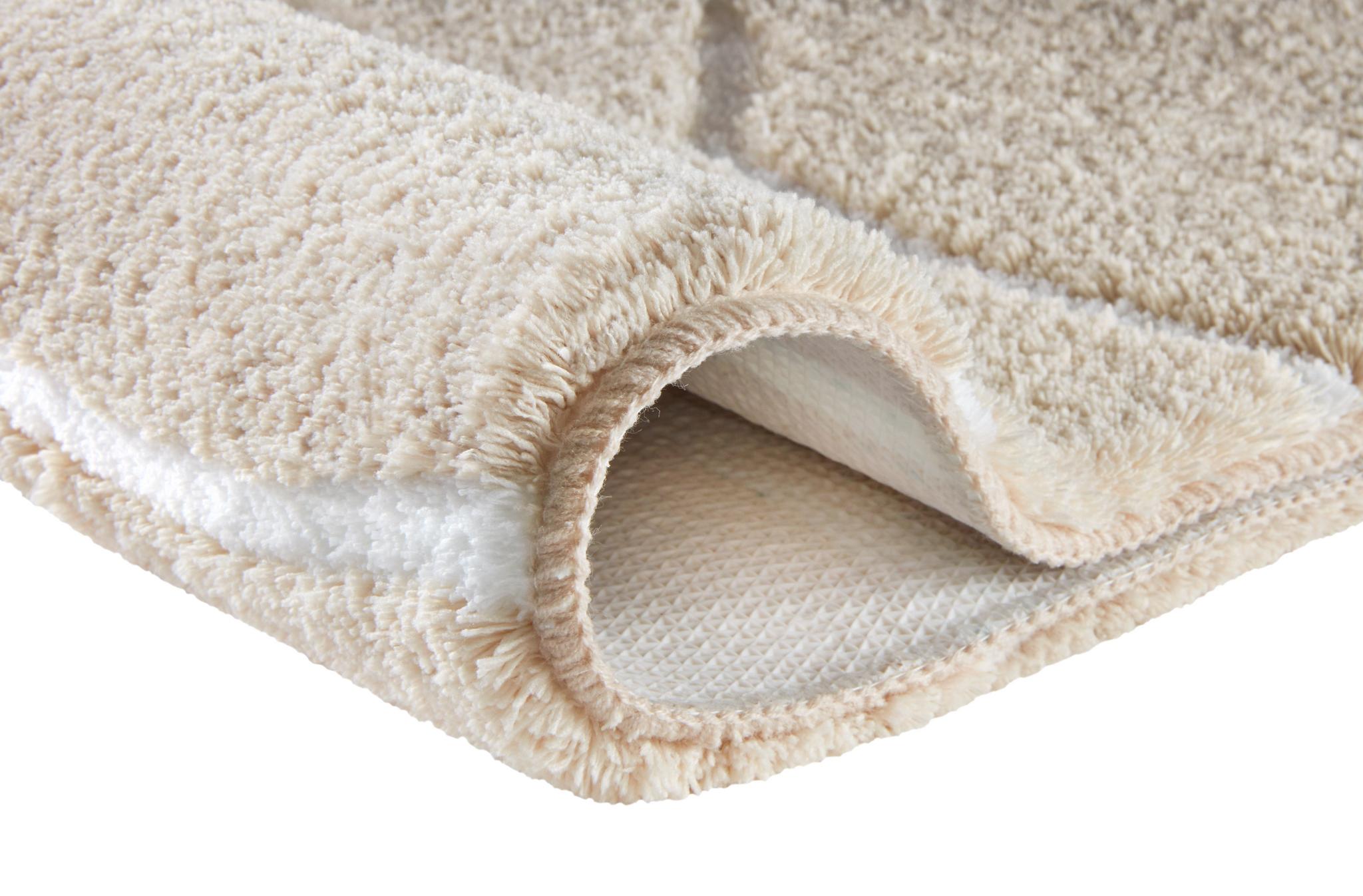 Cremefarbener flauschiger Badteppich mit rutschfester Unterseite.
