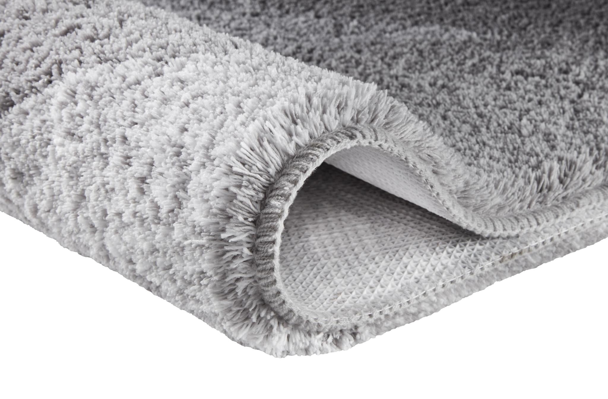 Grauer Hochflor-Teppich mit rutschhemmender Unterseite.