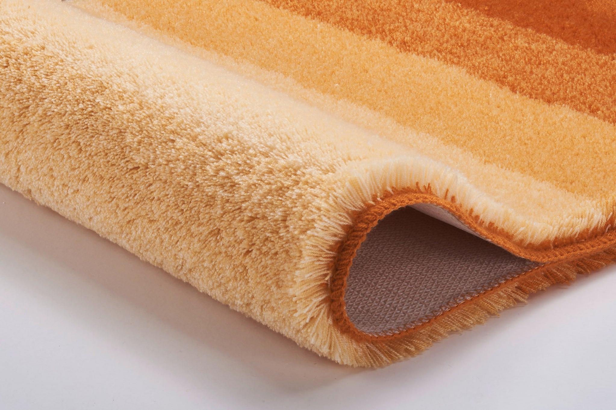 Weicher Badteppich mit dicken Streifen in warmen Orangetönen und Gelb
