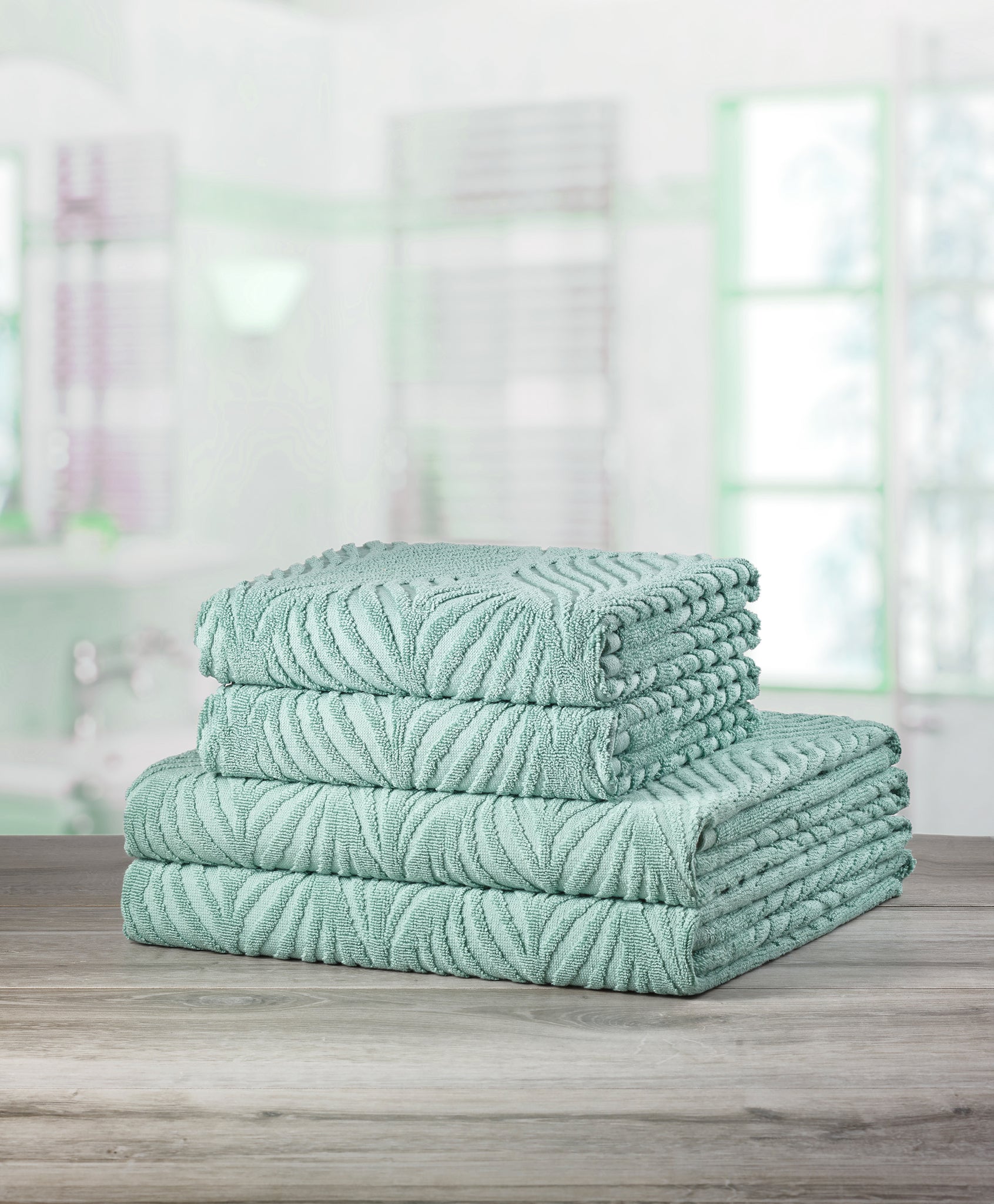 Gestapelte mintgrüne Handtücher mit Muster auf Holzoberfläche im Bad