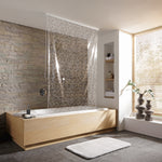 Moderne Badewanne mit Glasduschwand vor Steinwand und großem Fenster