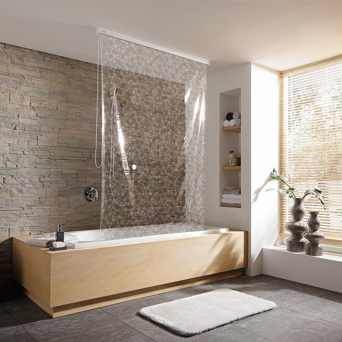Moderne Badewanne mit Glasduschwand vor Steinwand und großem Fenster