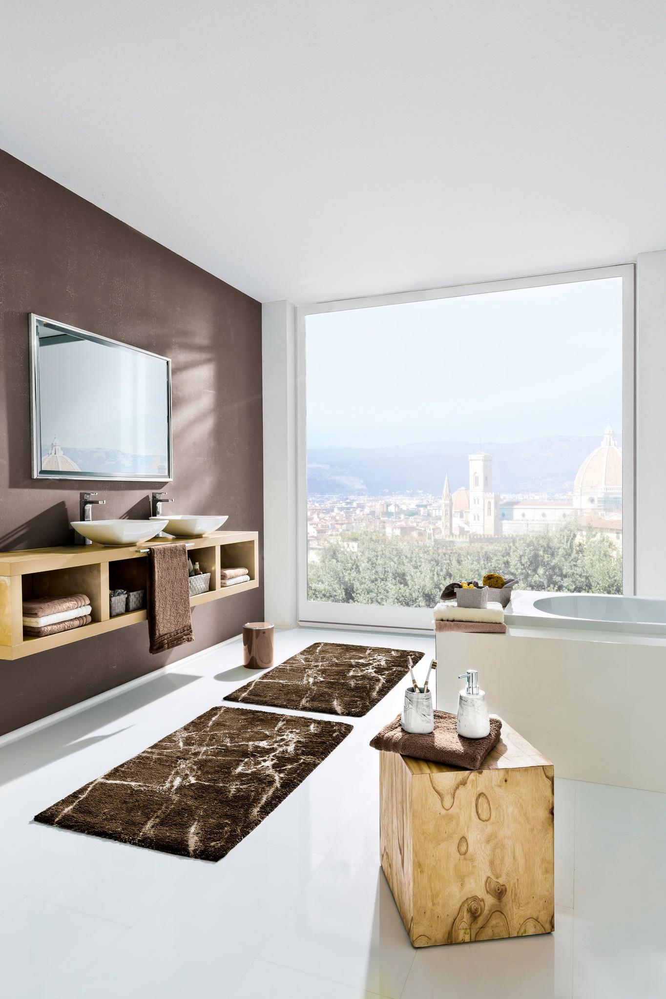 Modernes Bad mit Doppelwaschbecken, Wanne und braunen Badteppichen