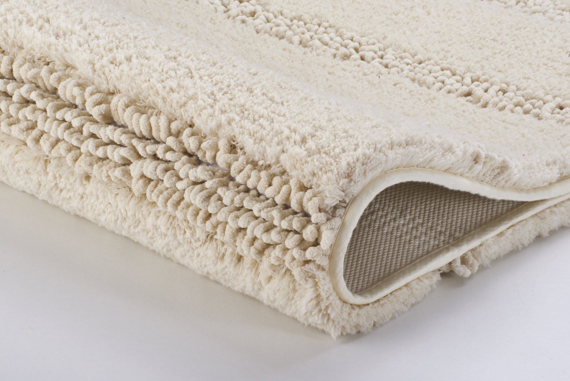 Gefaltete beige Badematte mit weicher, strukturierter Oberfläche aus Stoff