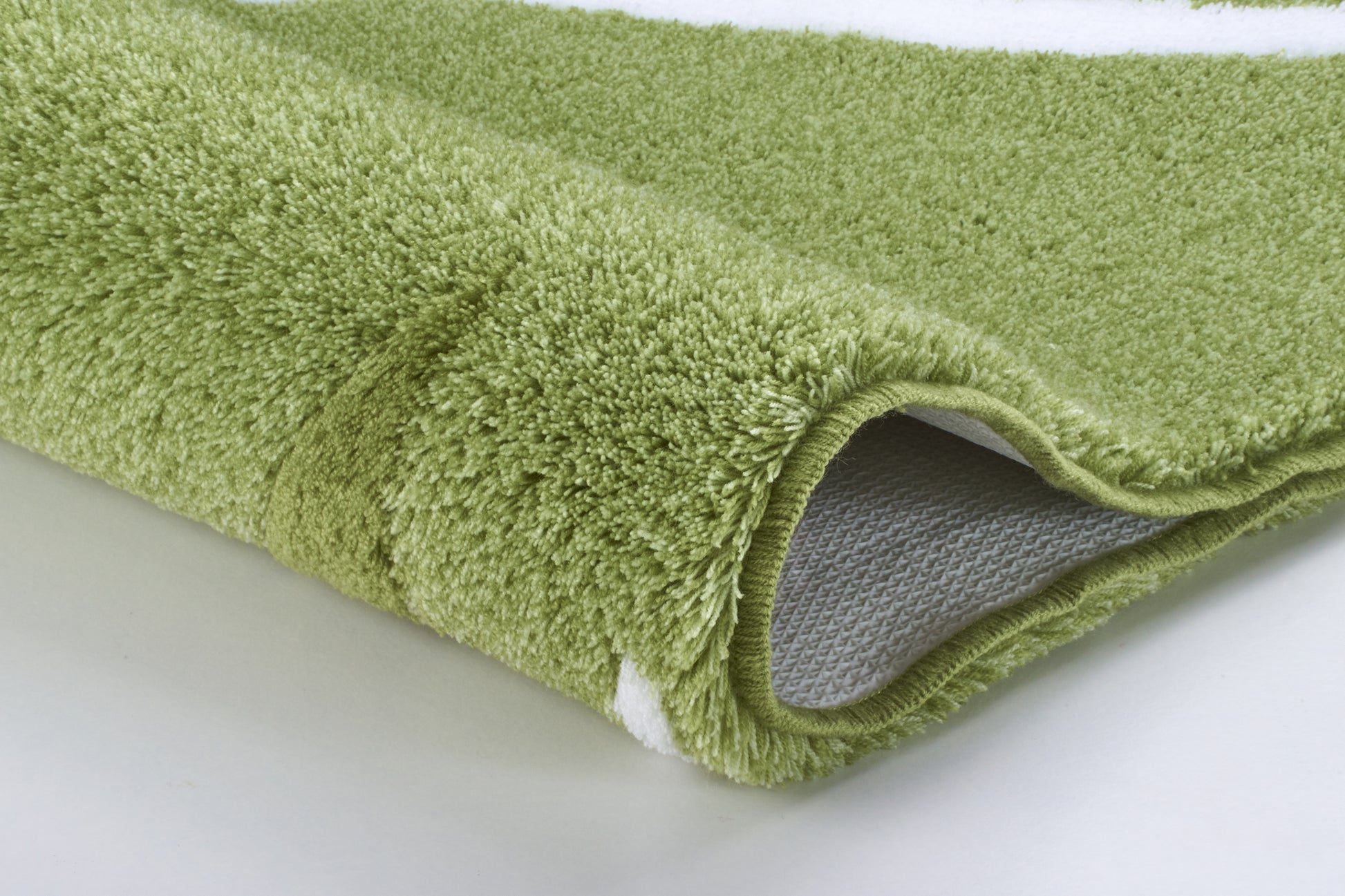 Detailansicht einer grünen Badematte mit weißem Muster am Rand unten