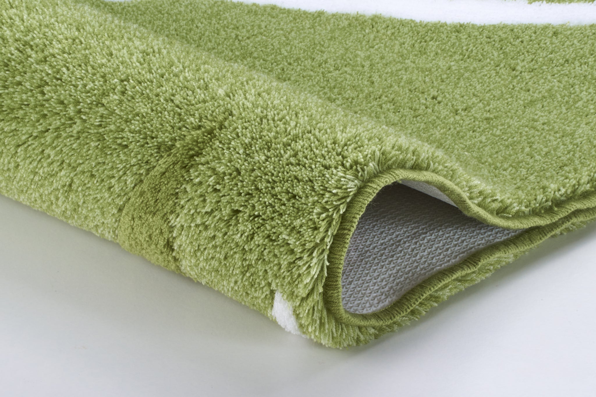 Detailansicht einer grünen Badematte mit weißem Muster am Rand unten