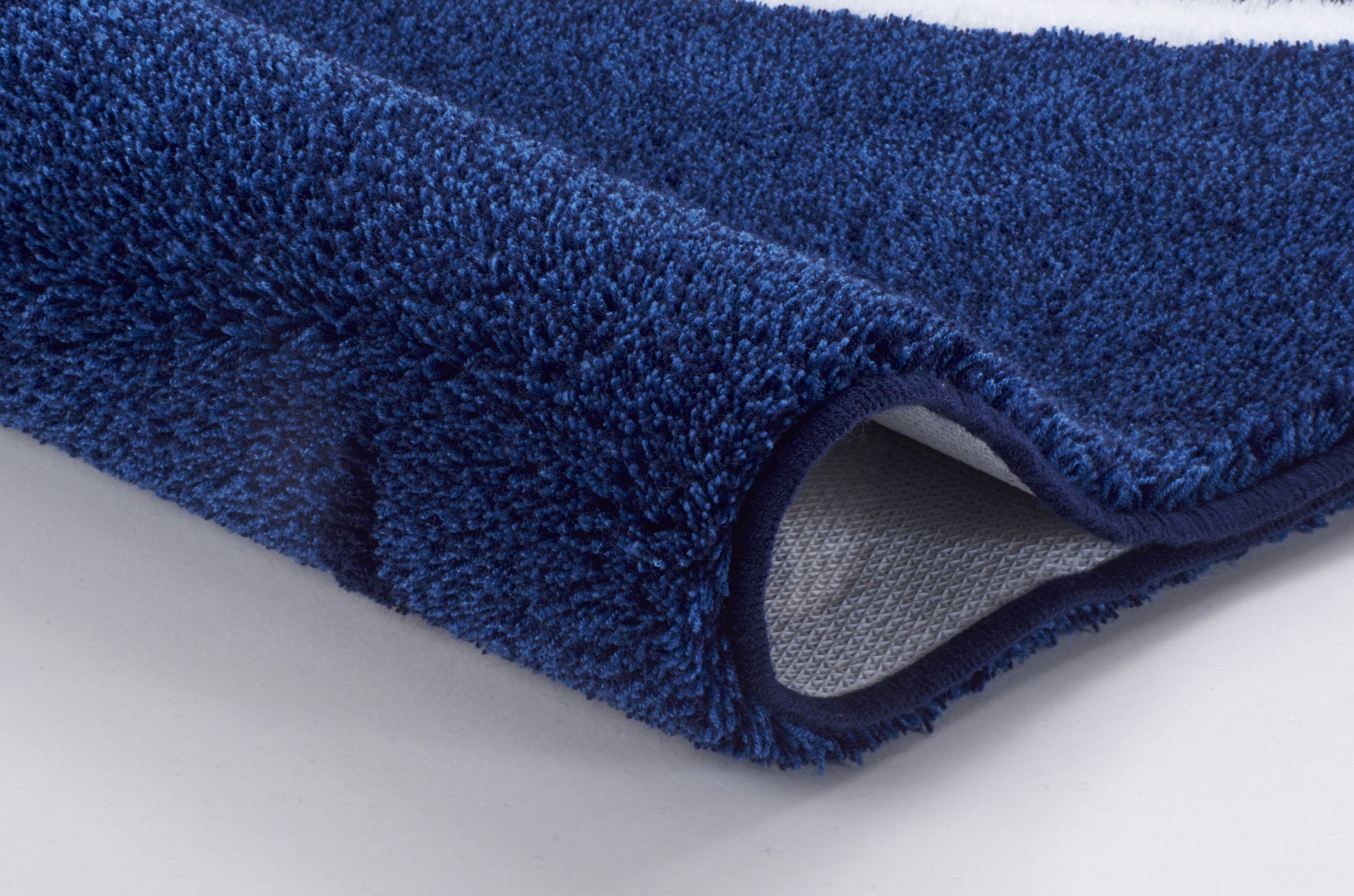 Nahaufnahme blaue Badematte mit flauschigem Flor und rutschfester Rückseite