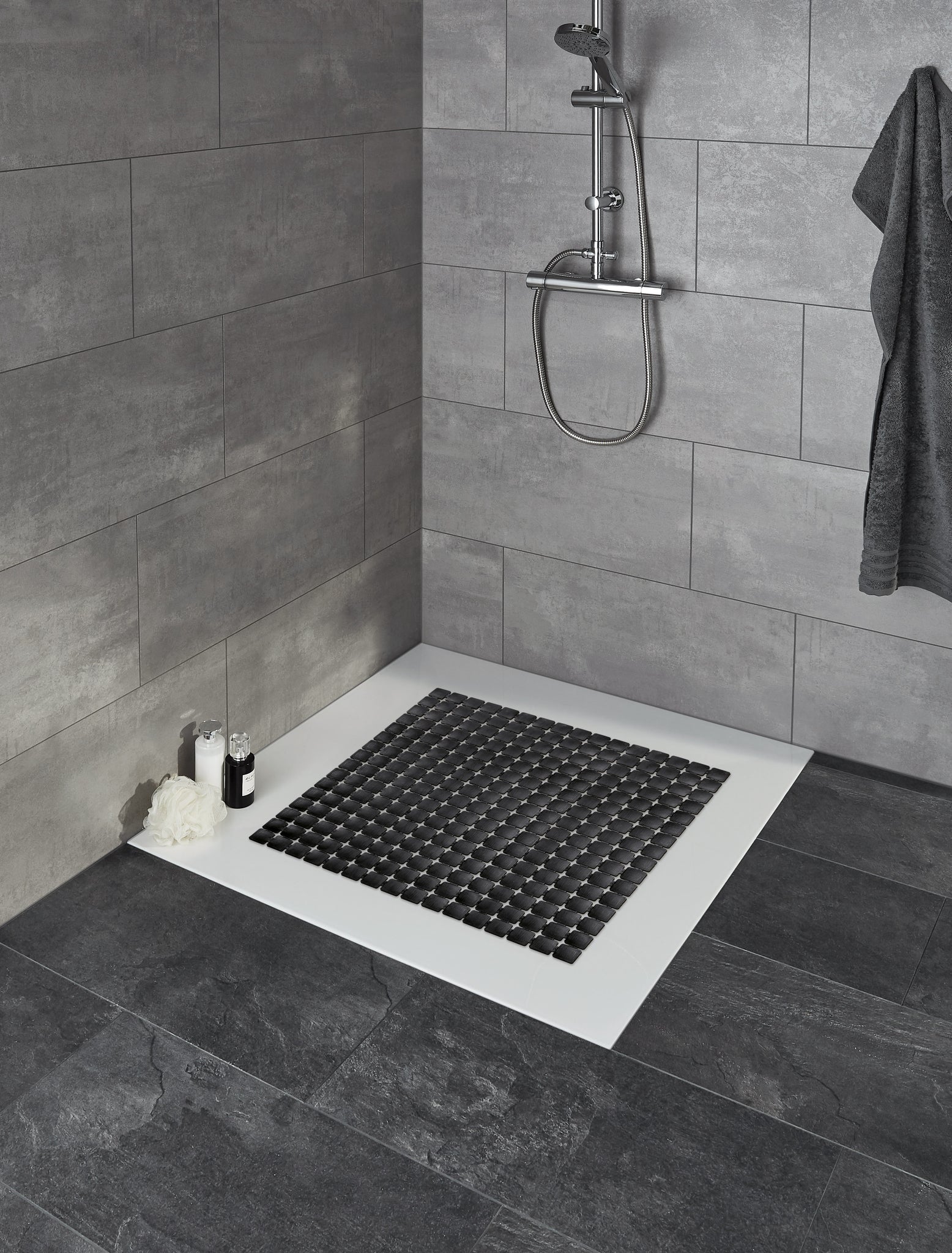 Duscheinlage GATTY Schwarz 54x54 cm liegt in moderner grau gefliester Dusche mit Wandarmatur.