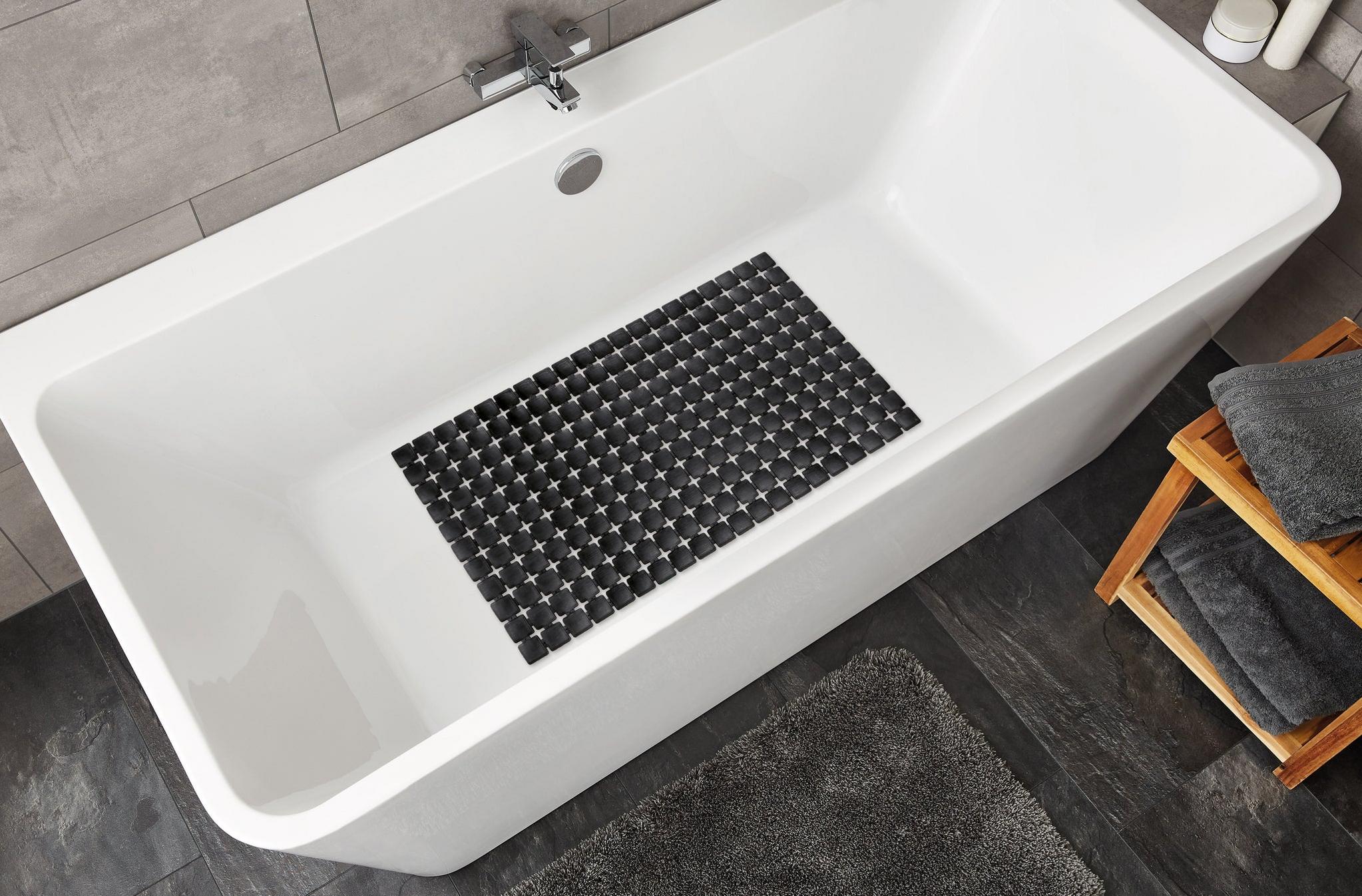 Weiße Badewanne mit schwarzer rutschfester Matte und grauen Handtüchern