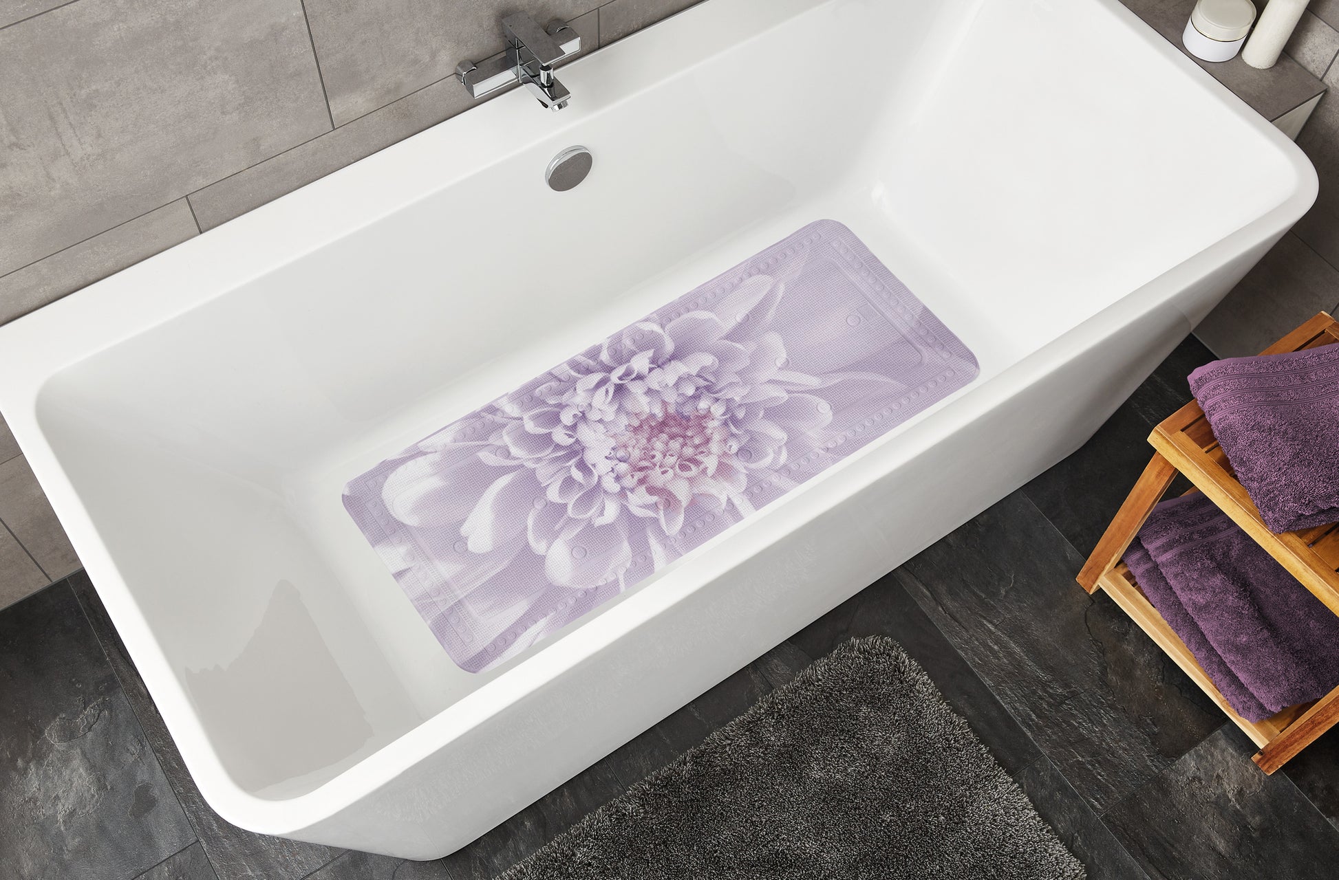 Weiße Badewanne mit lila Badematte mit Blumenmotiv innen unten zentriert