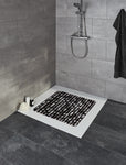 Moderne Dusche mit dunkel gemusterter Duschmatte auf weißer Duschwanne