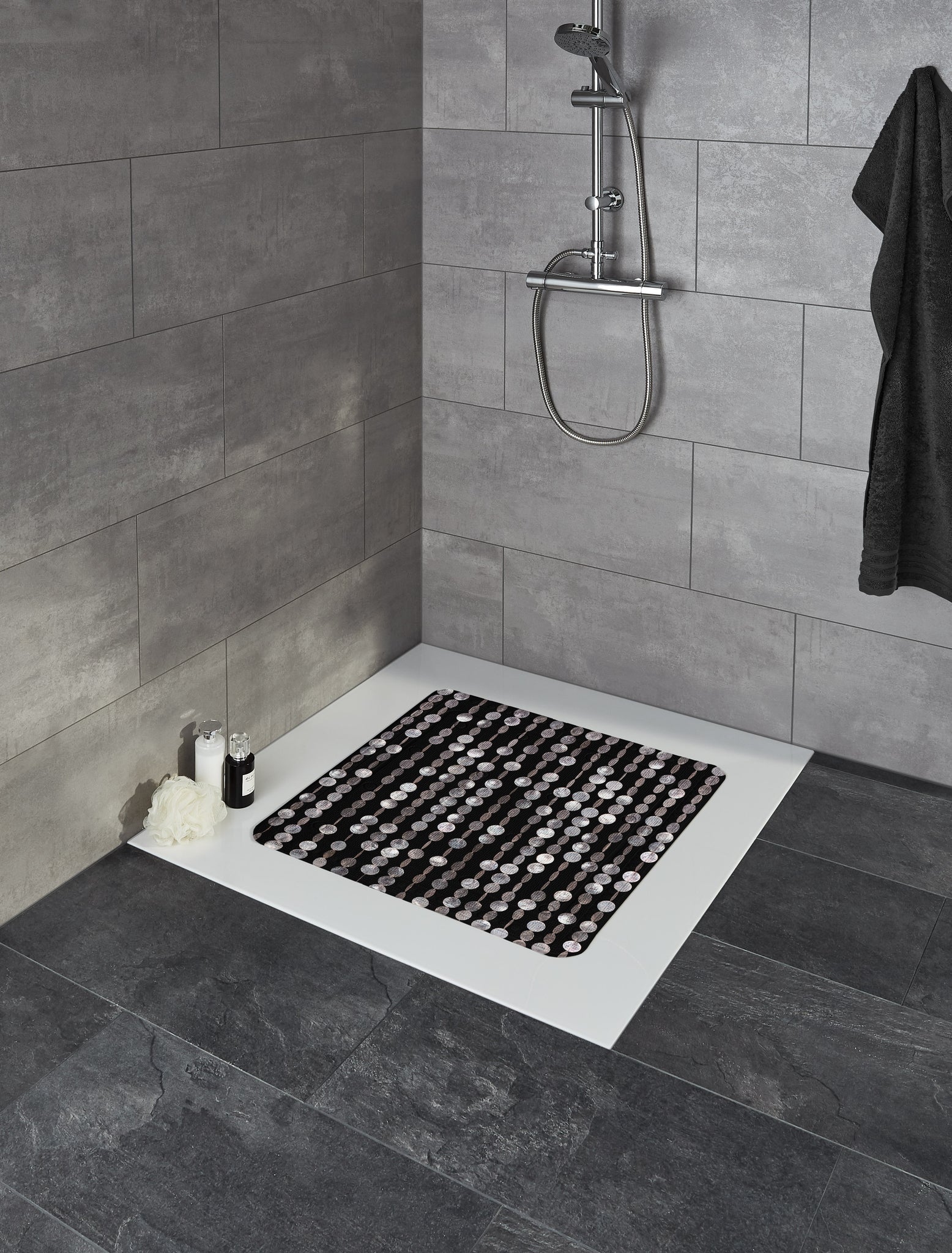 Duscheinlage PERLA Schwarz 55 x 55 cm liegt in moderner, grauer Fliesendusche mit Dekoartikeln.
