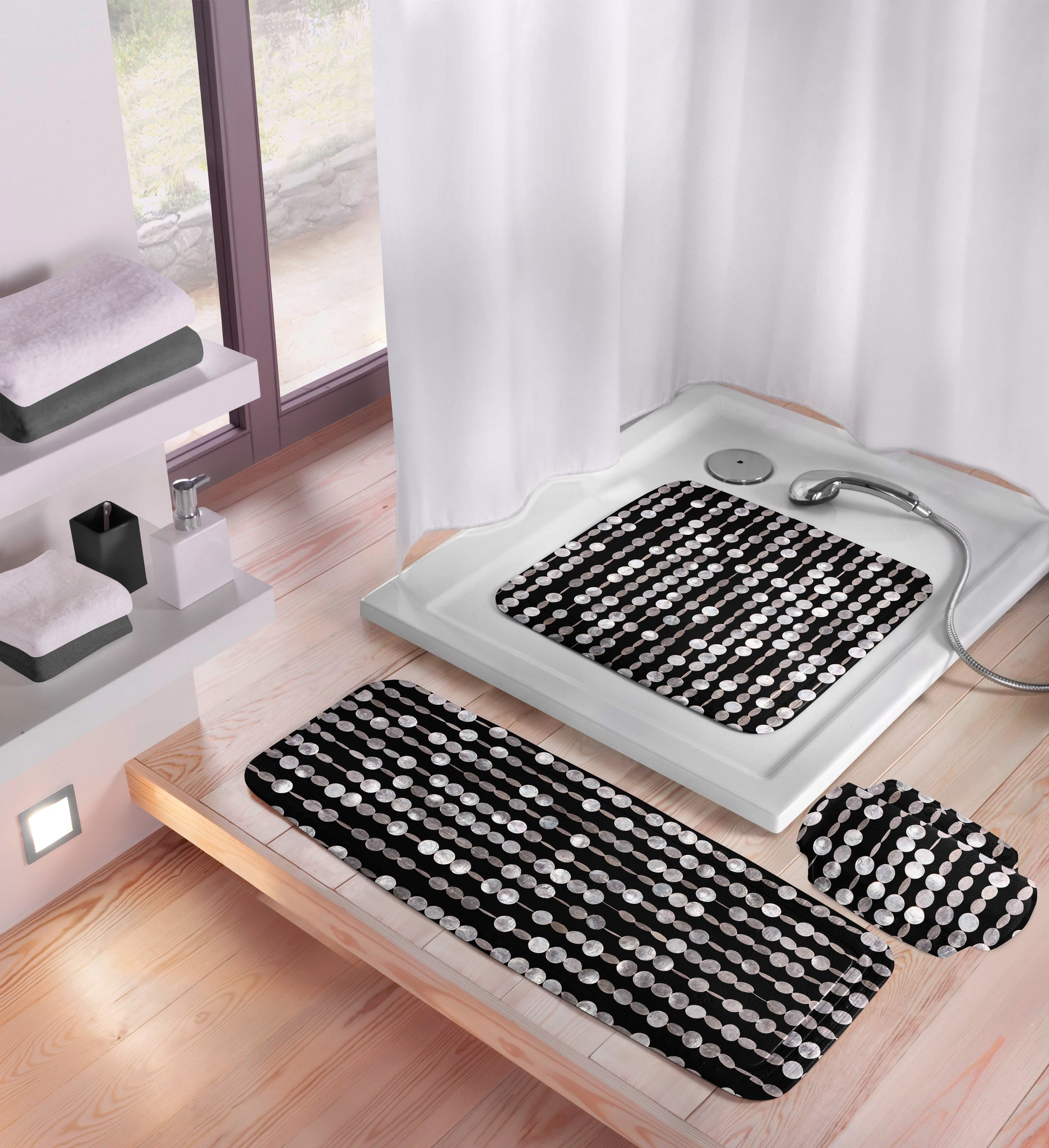 Nackenpolster PERLA Schwarz 32 x 22 cm liegt im Badezimmer neben passender Duschmatte in der Dusche.