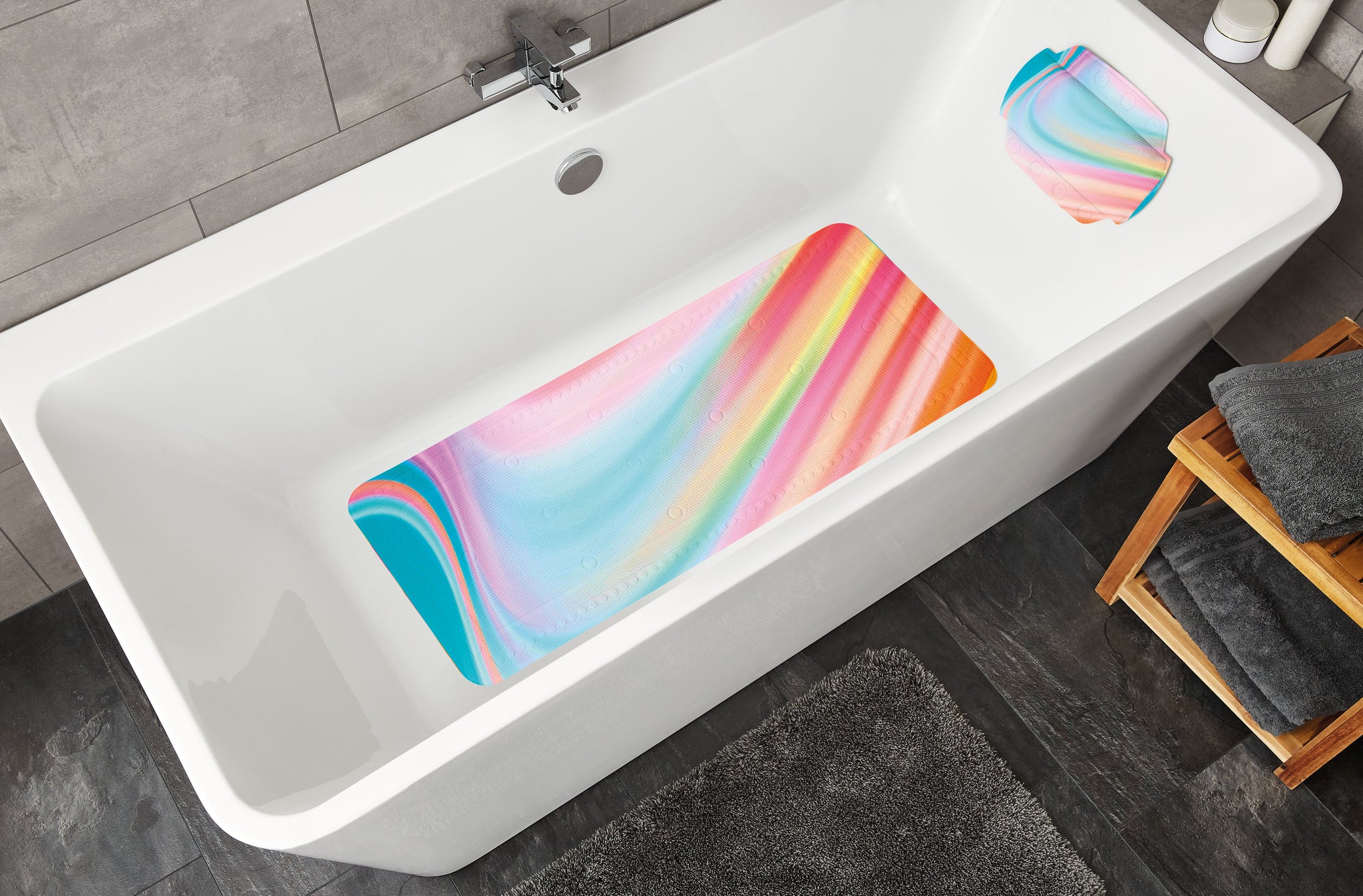 Weiße Badewanne mit bunter Anti-Rutsch-Matte und grauen Handtüchern