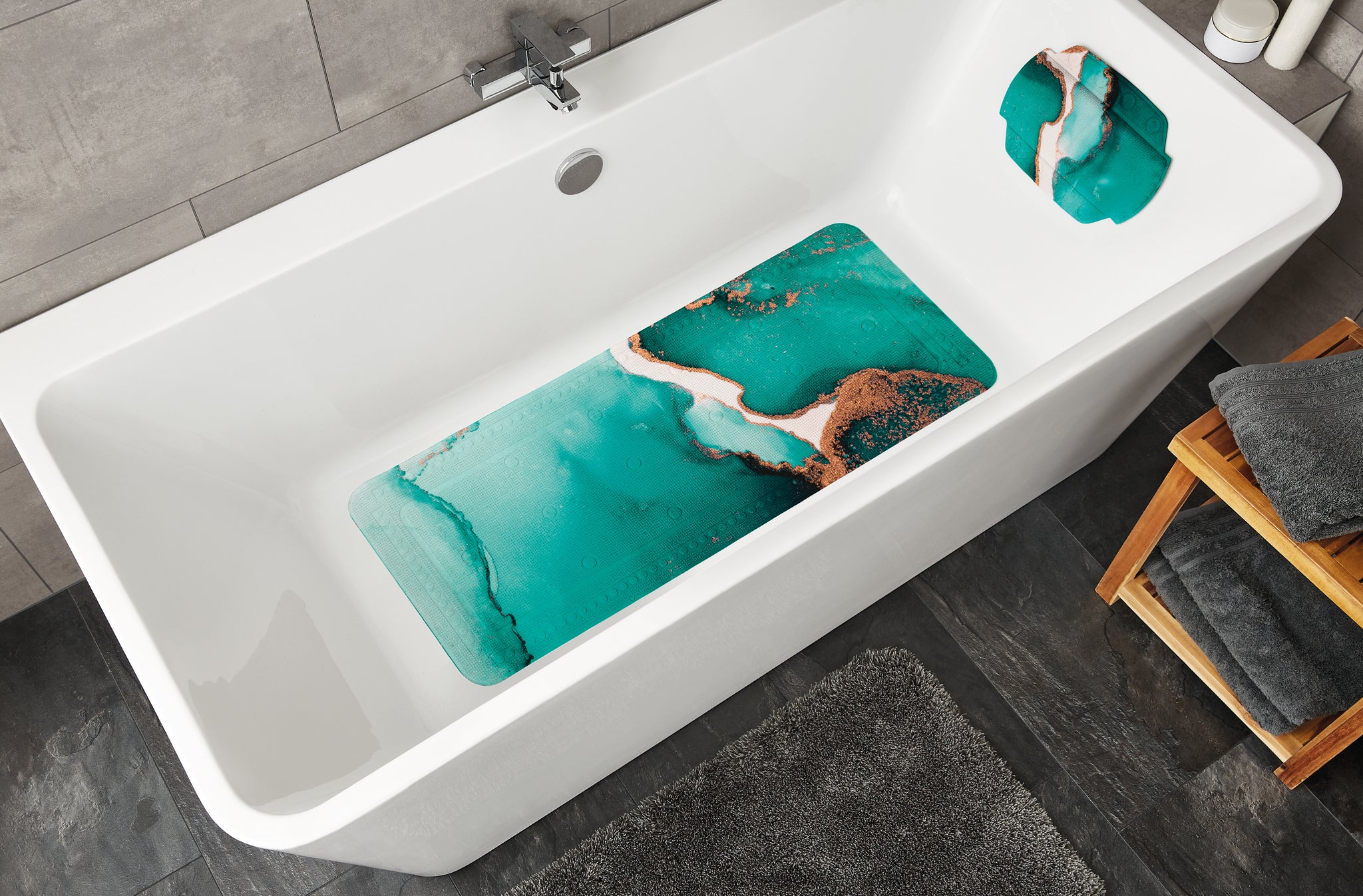 Weiße Badewanne mit türkis gemusterter Antirutschmatte und Kopfpolster