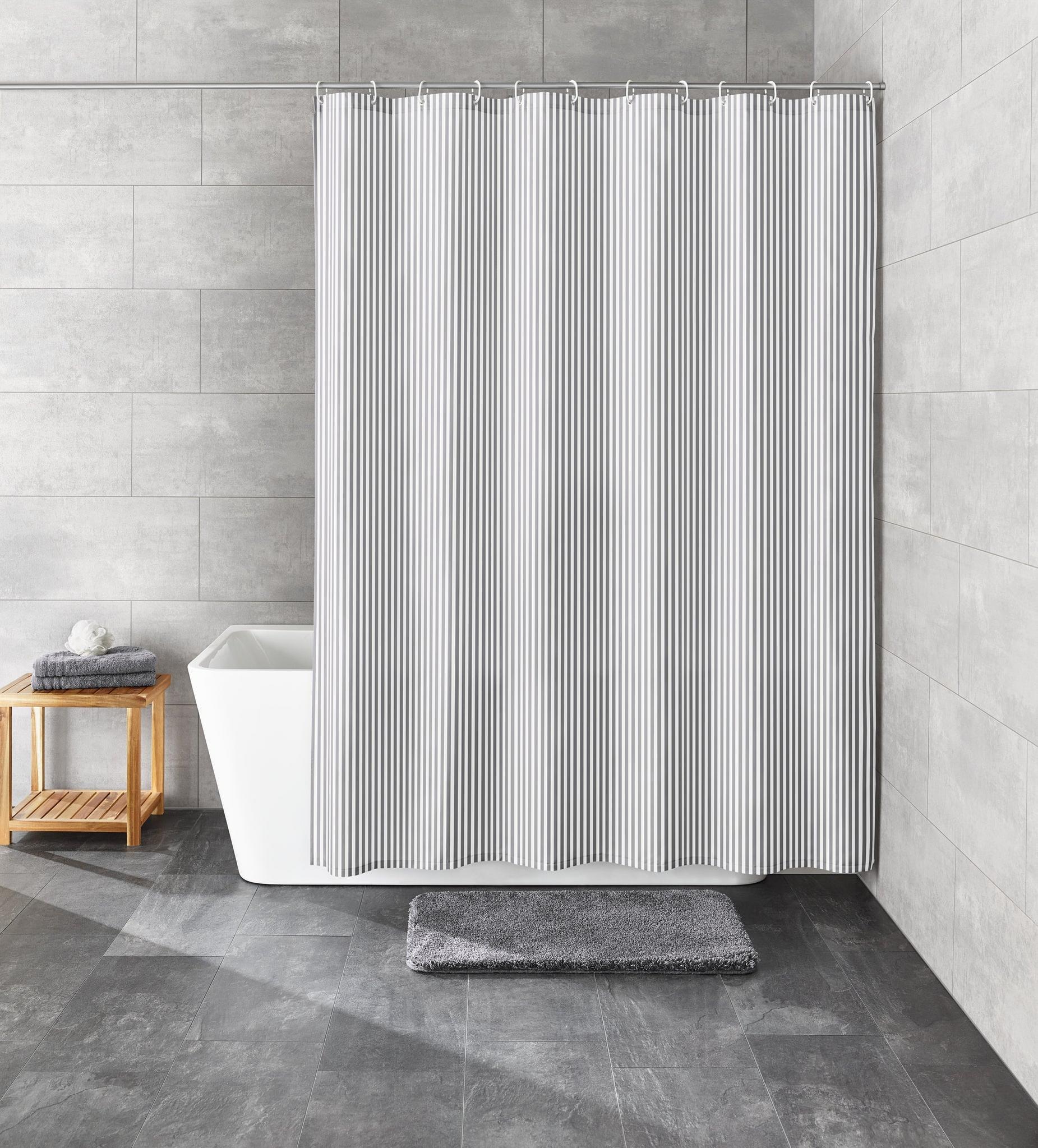 Grauer Stoff-Duschvorhang vor weißer Badewanne mit grauer Badematte
