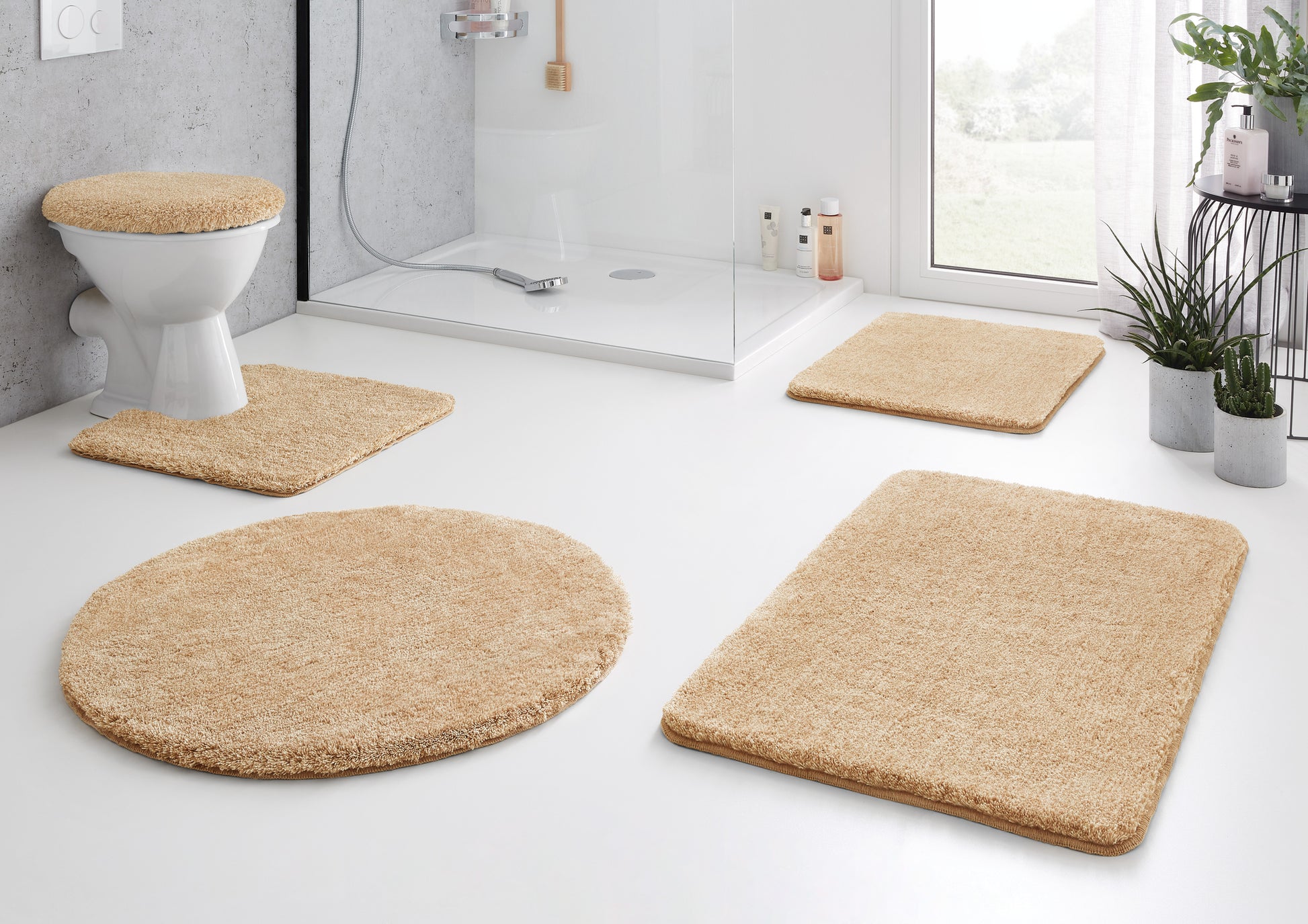 Beiges Badteppich-Set vor Dusche und WC auf weißem Badezimmerboden