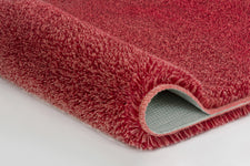 Nahaufnahme rosa Badteppich mit umgeschlagener Ecke und Rückseite