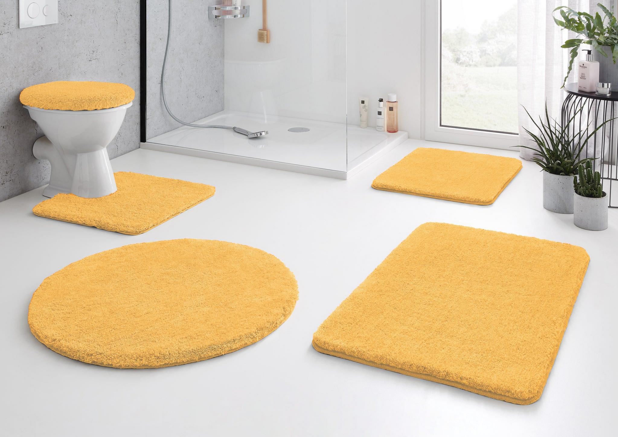 Gelbes Badezimmerteppich-Set mit WC-Deckelbezug auf weißem Boden