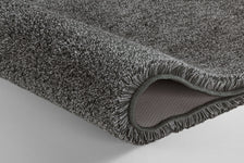 Graue, flauschige Badematte mit rutschfester Unterseite in Nahaufnahme