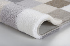 Nahaufnahme eines Badteppichs mit Karomuster in Grau, Beige und Weiß