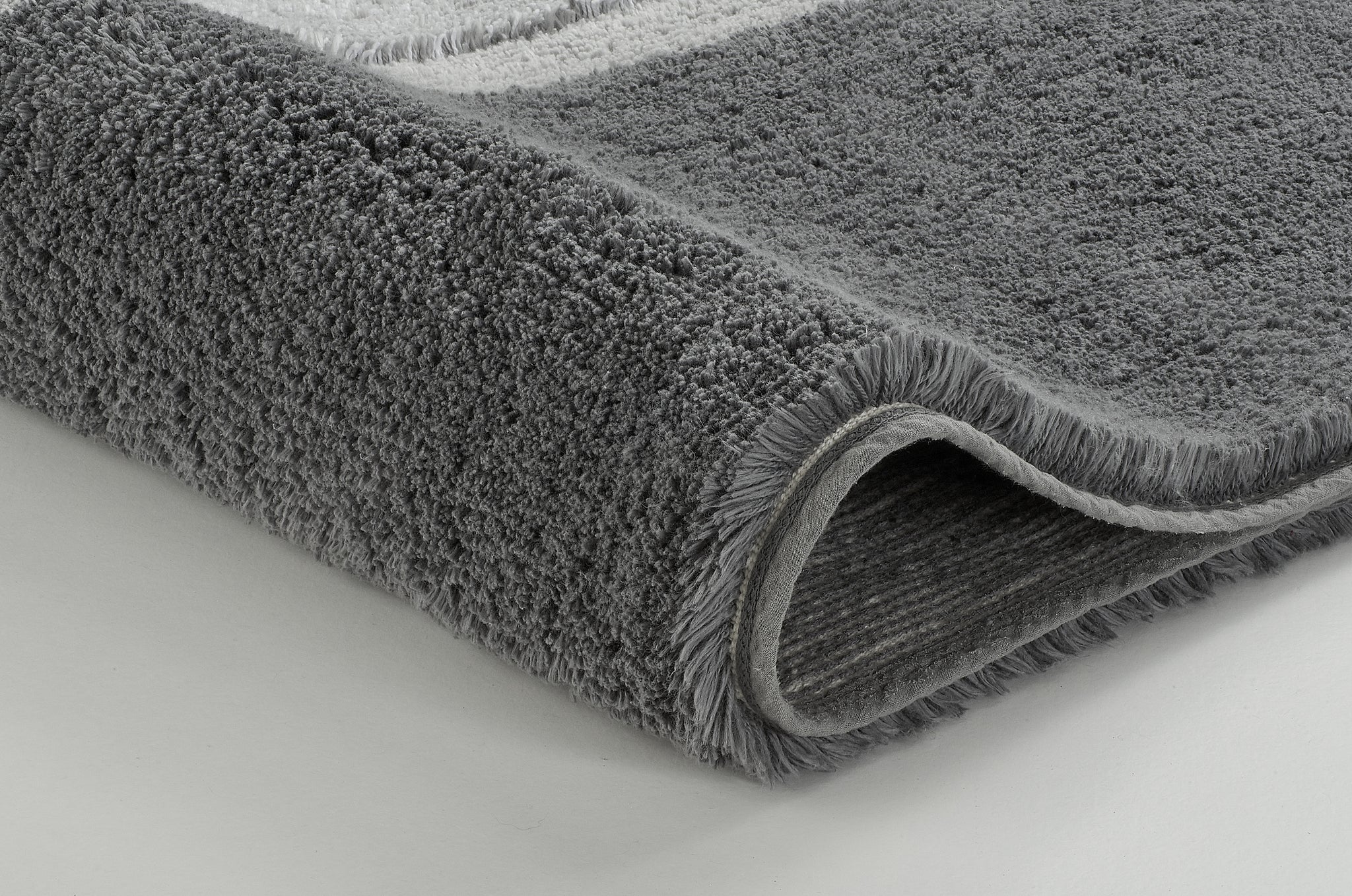 Graue, dichtflorige Badematte in Nahaufnahme auf hellem Untergrund