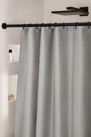 Grauer Duschvorhang an schwarzer Stange vor weißer Duschwand mit Ablagen