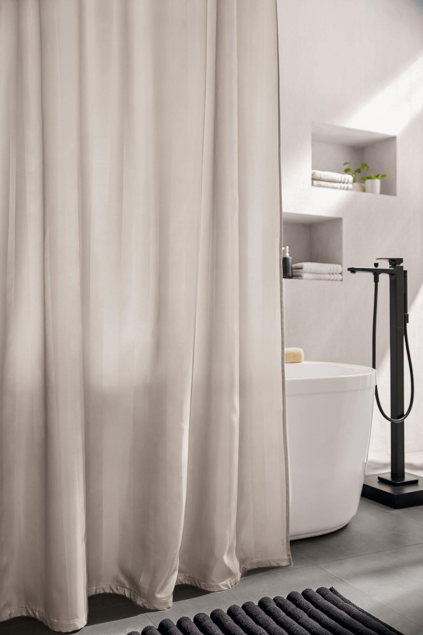 Beiges Duschvorhang vor freistehender Badewanne in modernem Designbad