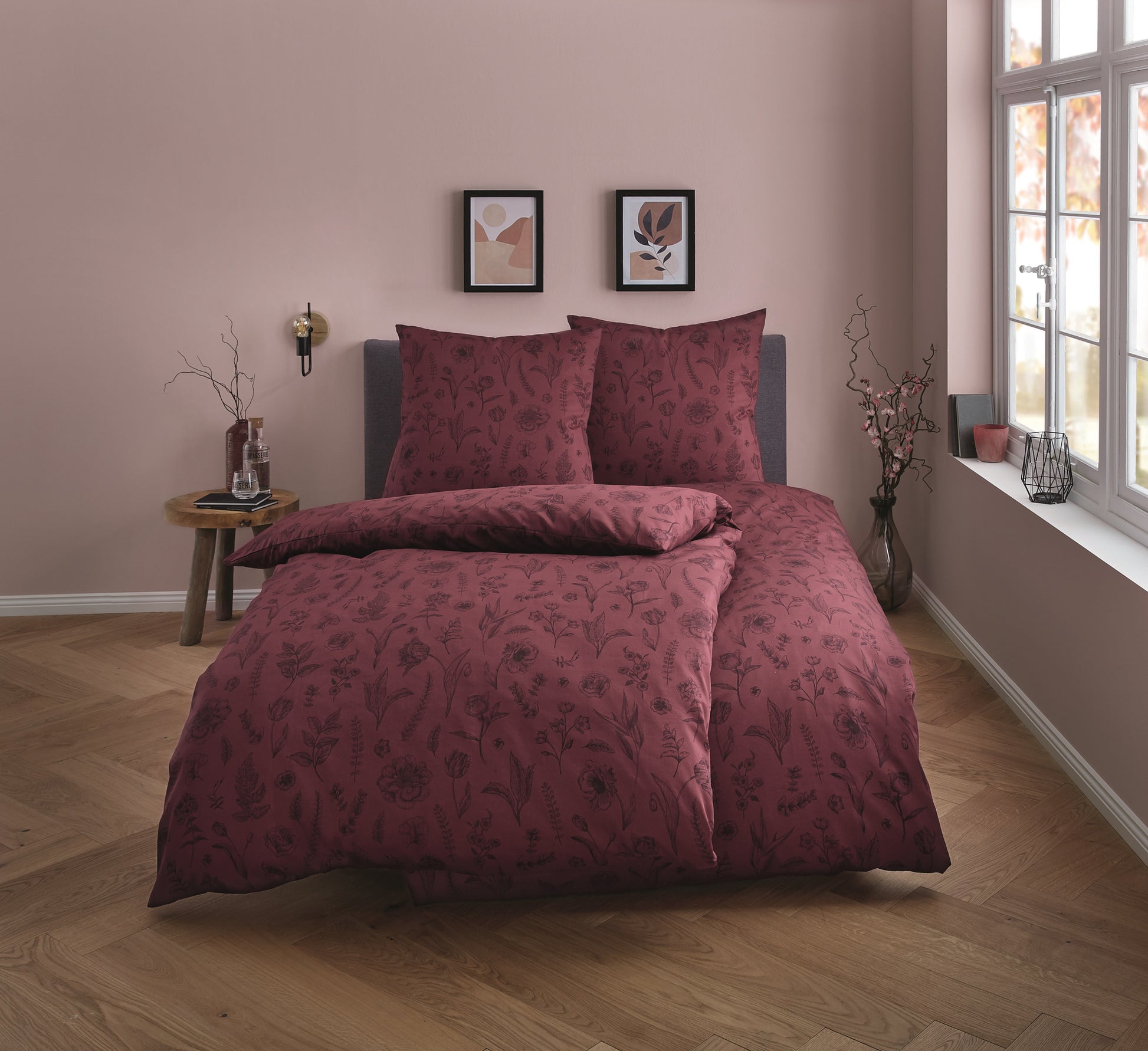 Rote Satin Bettwäsche mit floralem Muster auf einem Bett in einem modern eingerichteten Schlafzimmer.