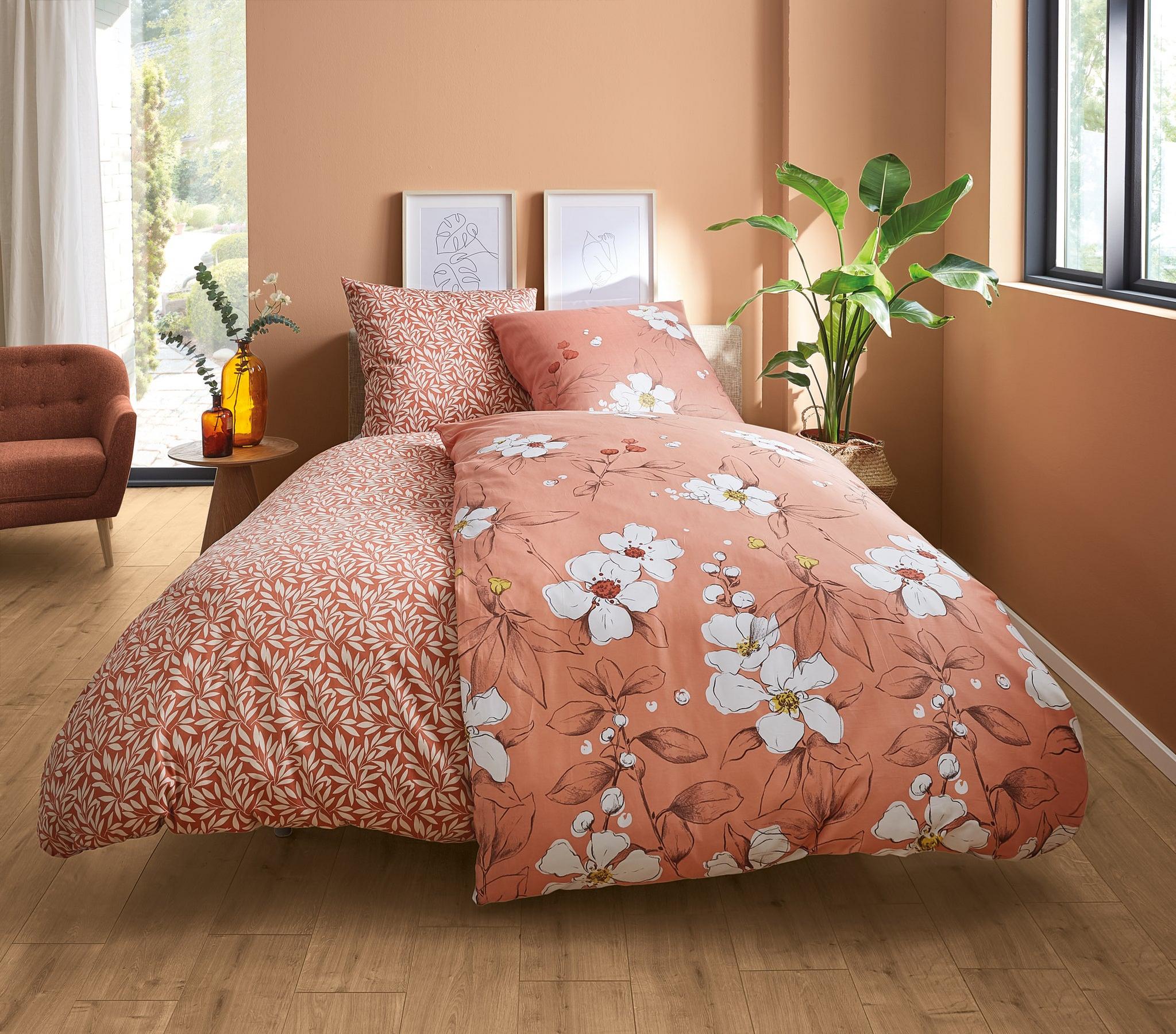 Doppelbett mit apricotfarbener Blumen-Bettwäsche in hellem Schlafzimmer