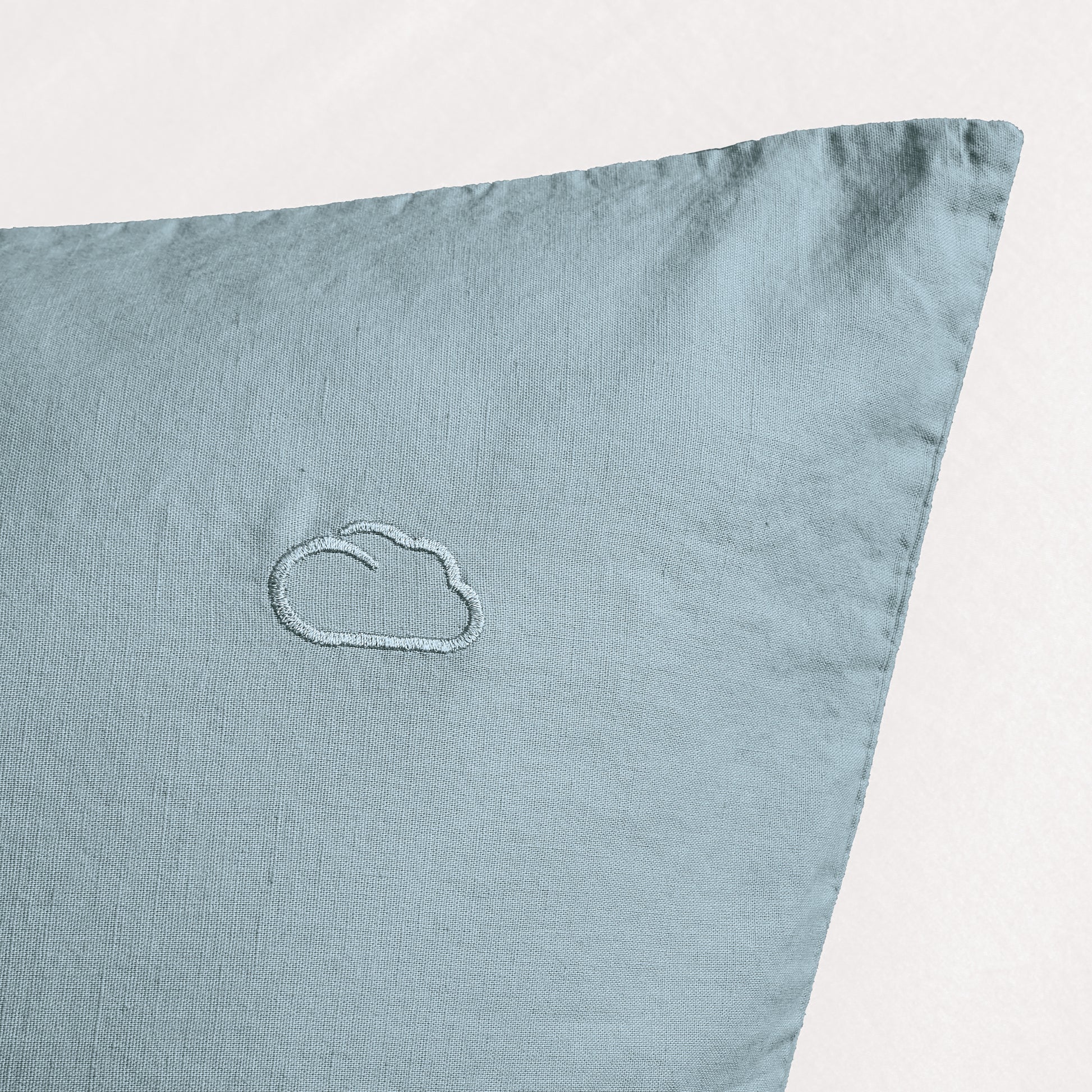 Hellblaue Kissenhülle aus Leinen mit kleiner eingestickter Wolke vorn