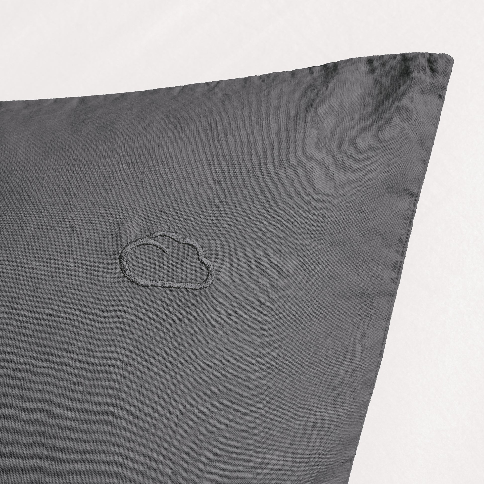 Graues Kopfkissen mit eingesticktem Wolkenmotiv in der oberen Ecke