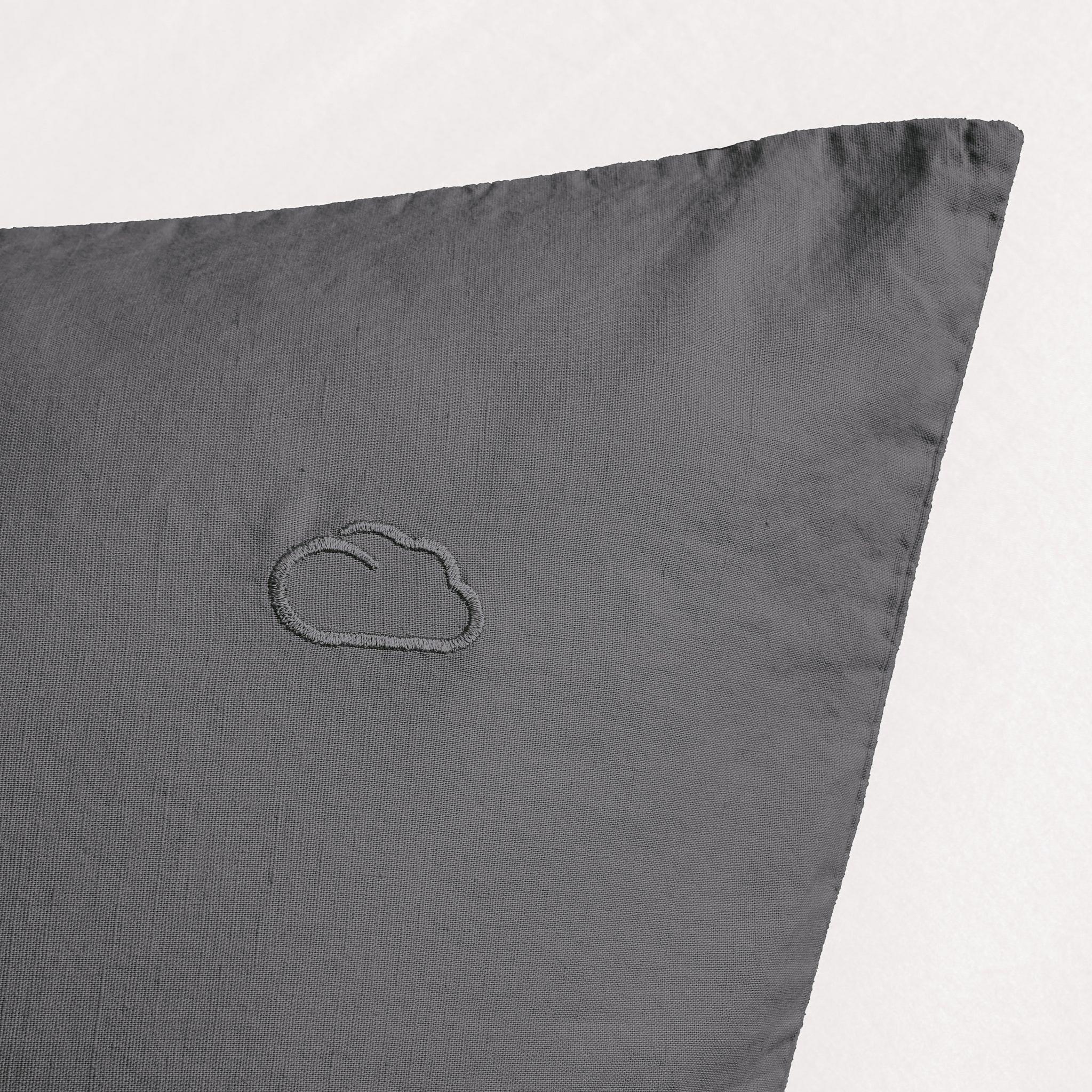 Graues Kopfkissen mit eingesticktem Wolkenmotiv in der oberen Ecke