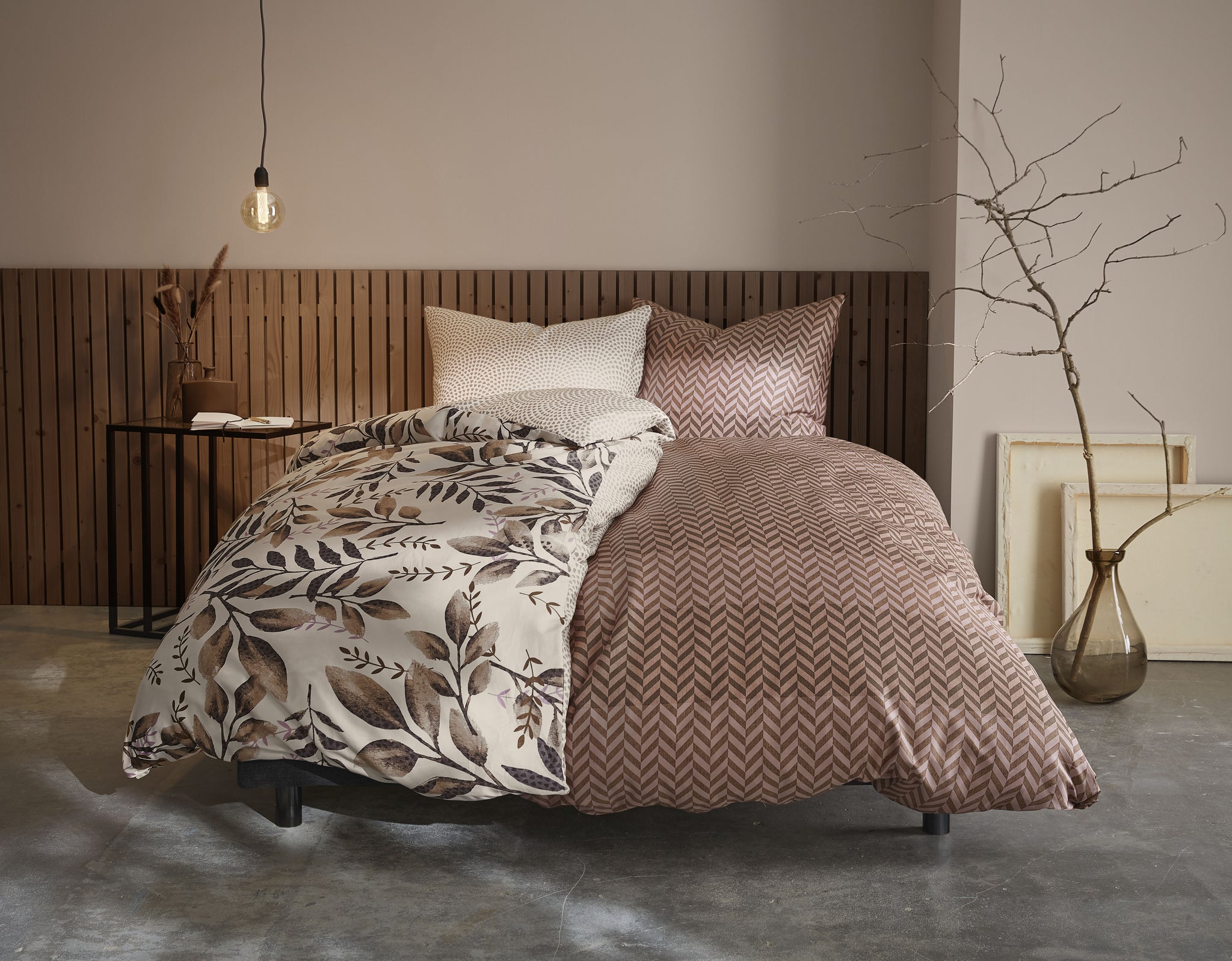 Gemütliches Bett mit gemusterter Bettwäsche in Braun- und Cremetönen