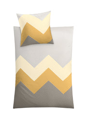 Bettwäsche Satin LYKKE Goldgelb mit Zickzackmuster in 135x200 cm und 80x80 cm ist auf dem Bild zu sehen.