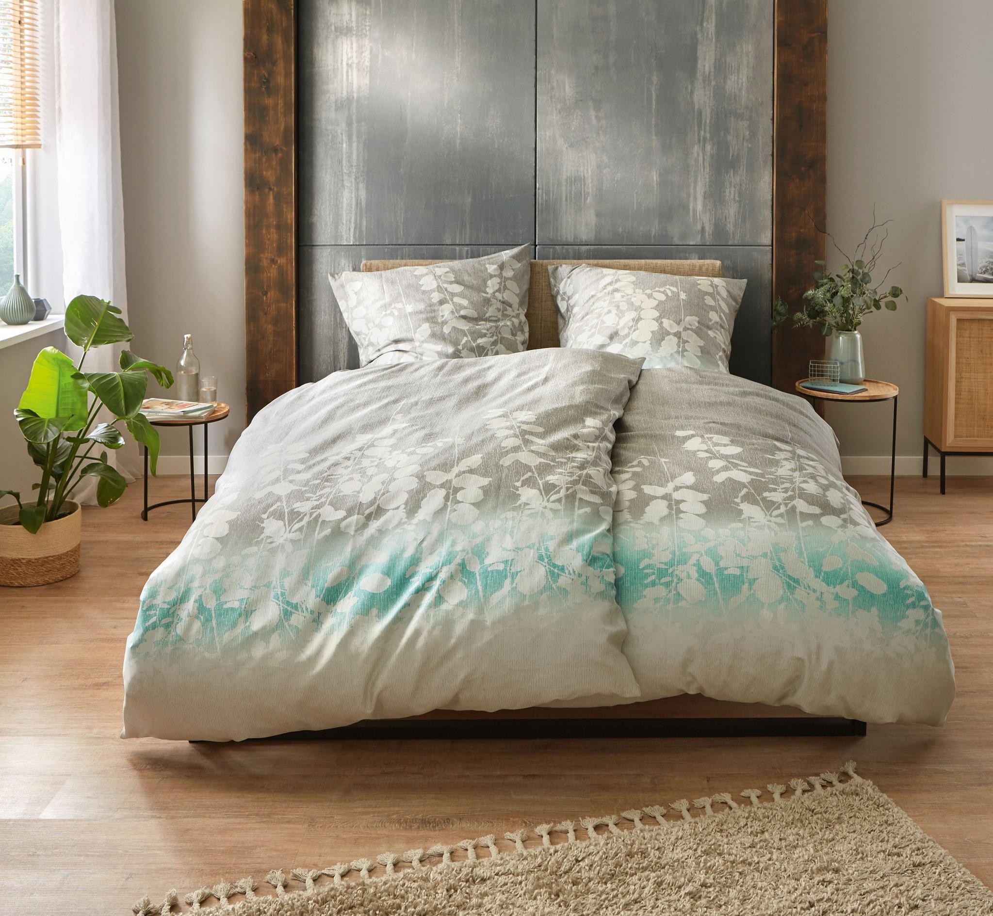 Doppelbett mit grauer Bettwäsche und Blumenmuster im gemütlichen Zimmer
