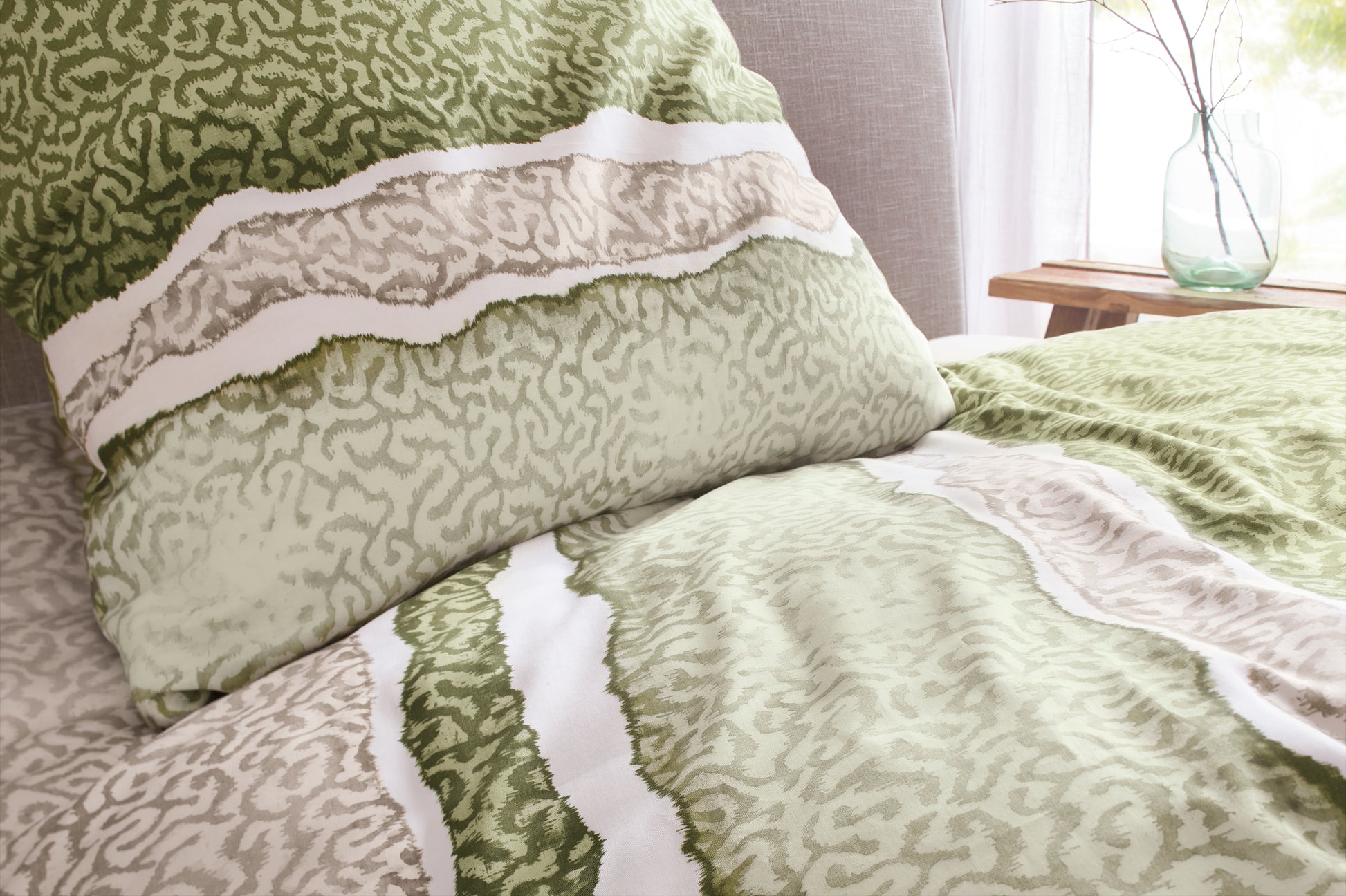 Bettwäsche Satin MAREA Dill mit Kissen 80x80 und Decke 135x200 in Grün-Beige auf Bett im Detail.