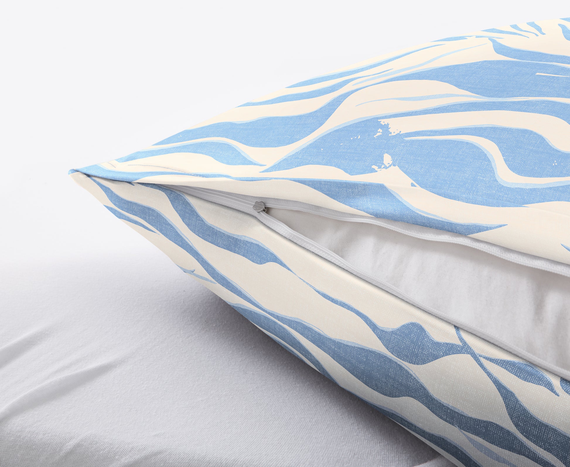 Detailansicht Kissen mit blau-weißem Bezug und Reißverschluss auf Bett