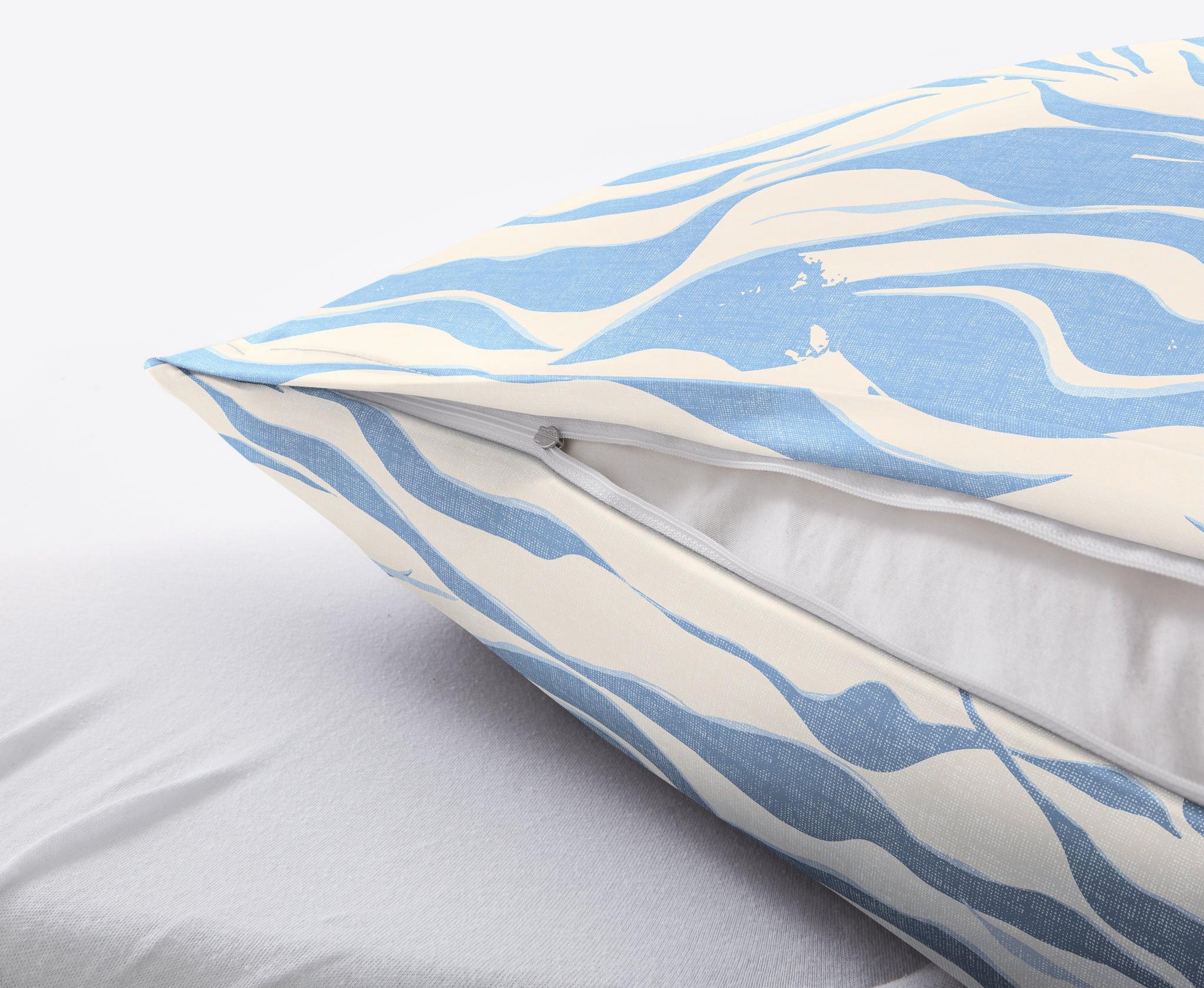 Detailansicht Kissen mit blau-weißem Bezug und Reißverschluss auf Bett