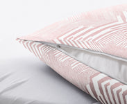 Rosa-weiß gemusterter Kissenbezug mit Reißverschluss auf weißem Laken