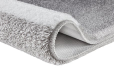 Ein grau-weißer Hochflor-Teppich zeigt seine weiche Struktur im Detail.