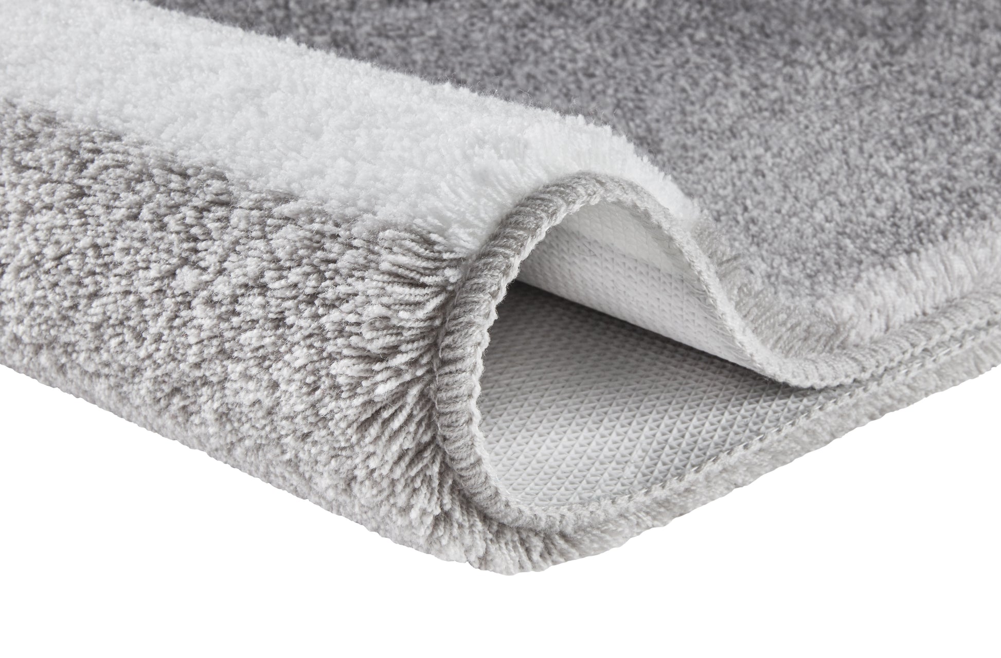 Ein grau-weißer Hochflor-Teppich zeigt seine weiche Struktur im Detail.