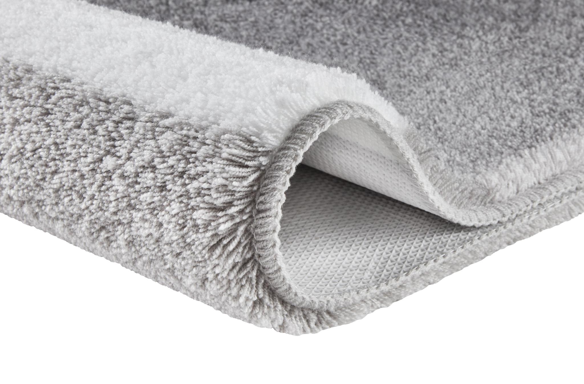 Ein grau-weißer Hochflor-Teppich zeigt seine weiche Struktur im Detail.