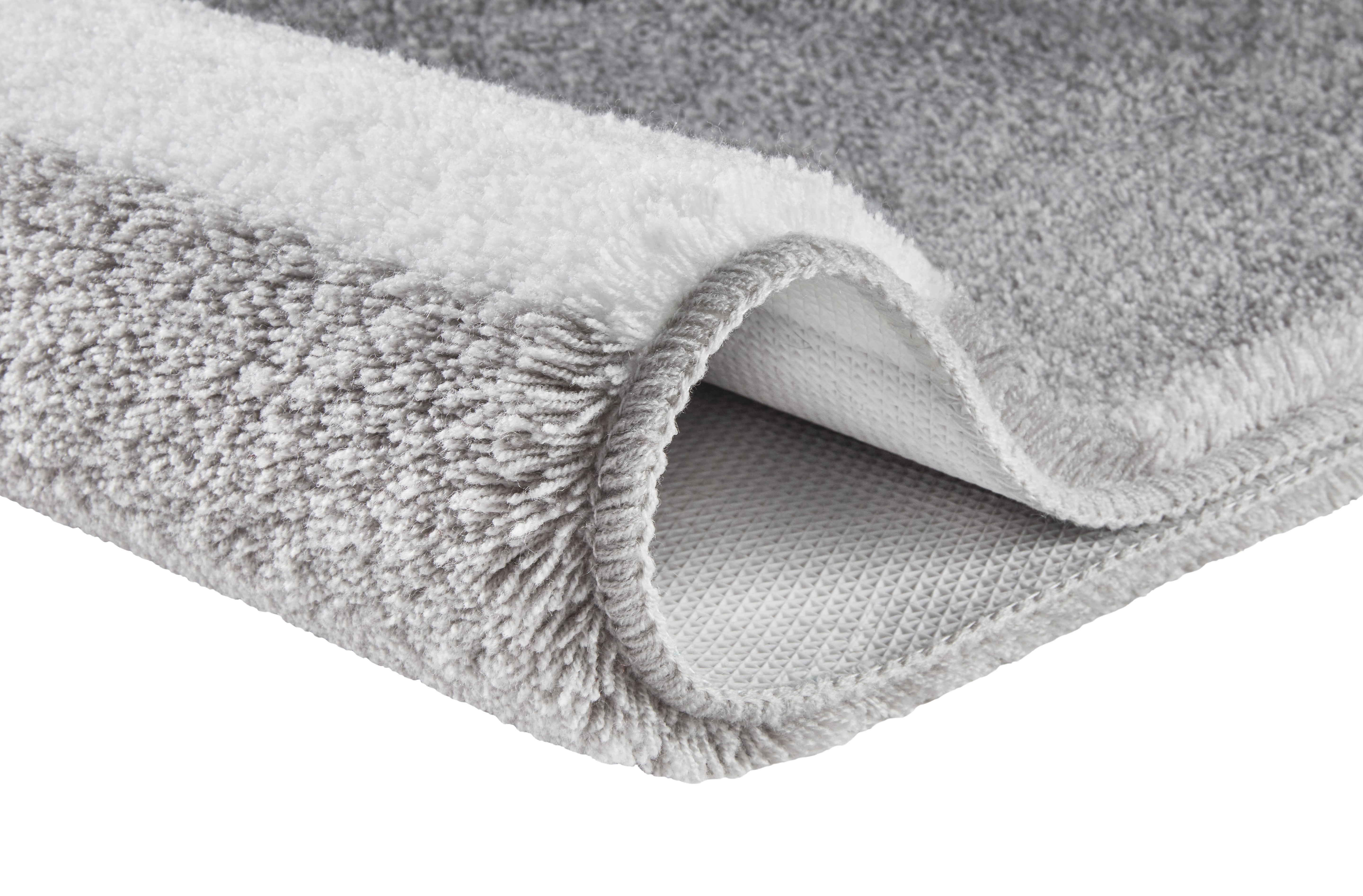 Ein grau-weißer Hochflor-Teppich zeigt seine weiche Struktur im Detail.
