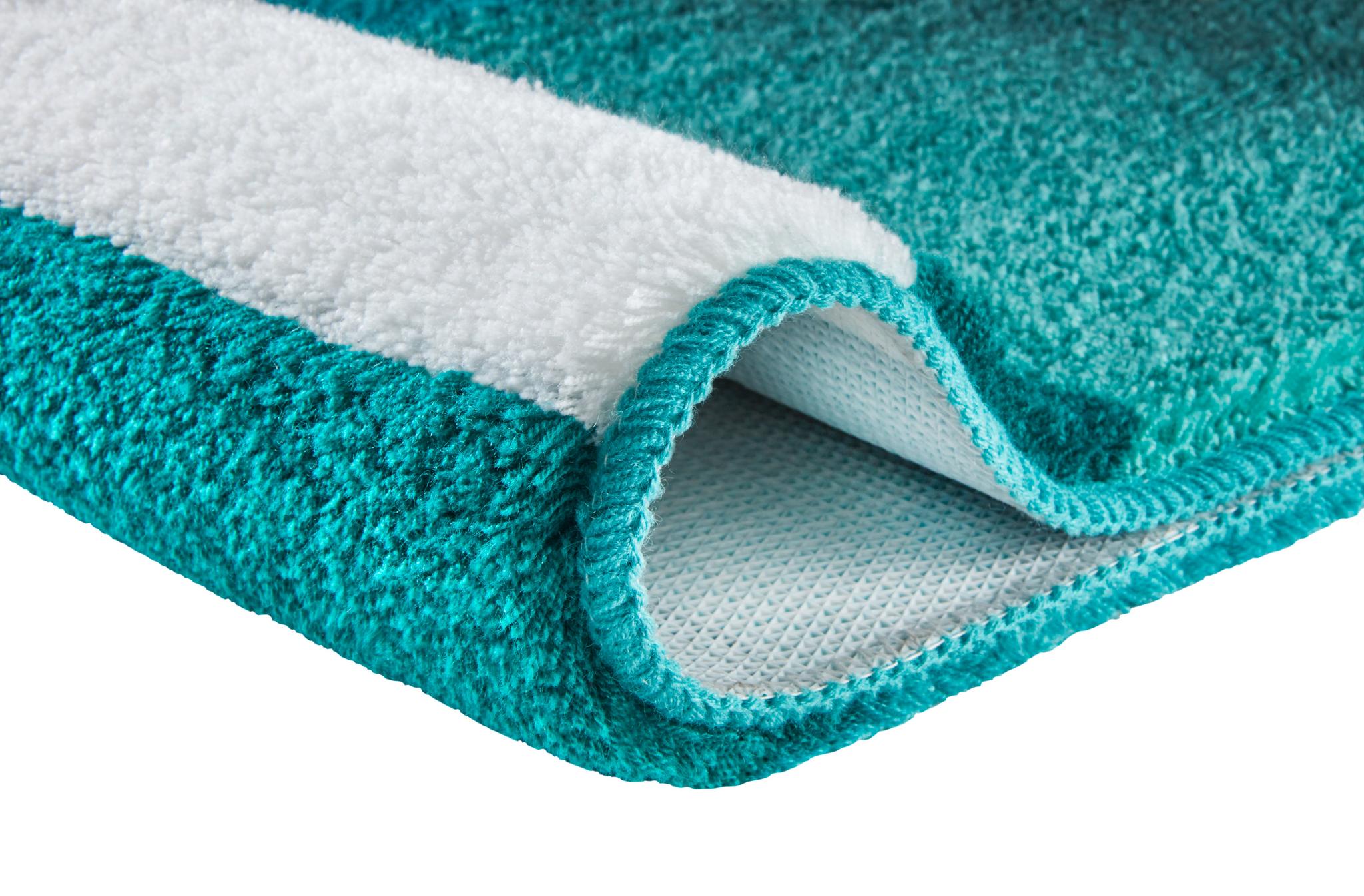 Ein türkis-weißer Hochflor-Teppich zeigt seine flauschige Struktur.