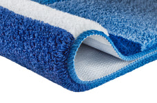 Ein blau-weißer Teppich zeigt weiche Struktur und Fransen im Detail.