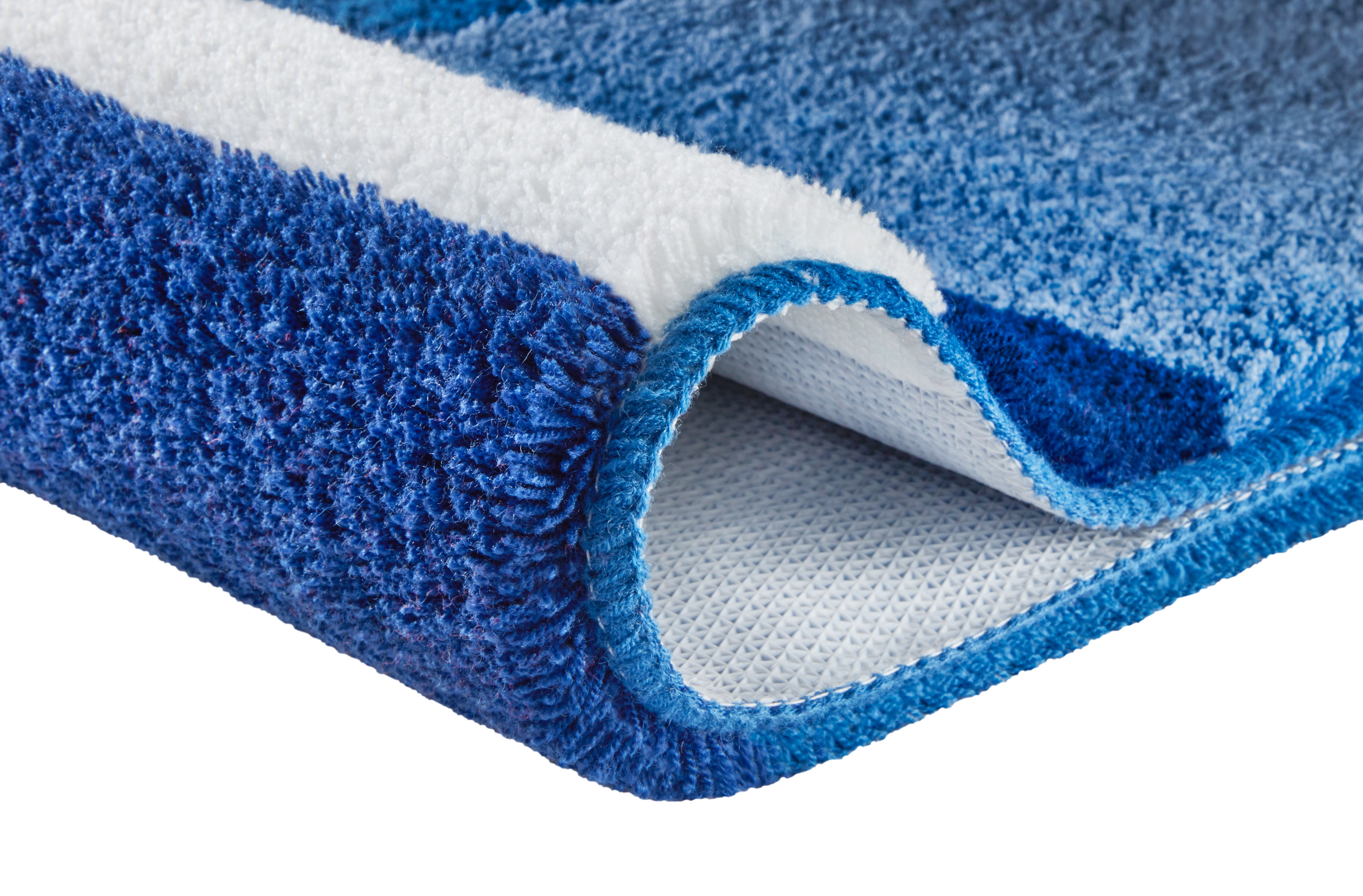 Ein blau-weißer Teppich zeigt weiche Struktur und Fransen im Detail.