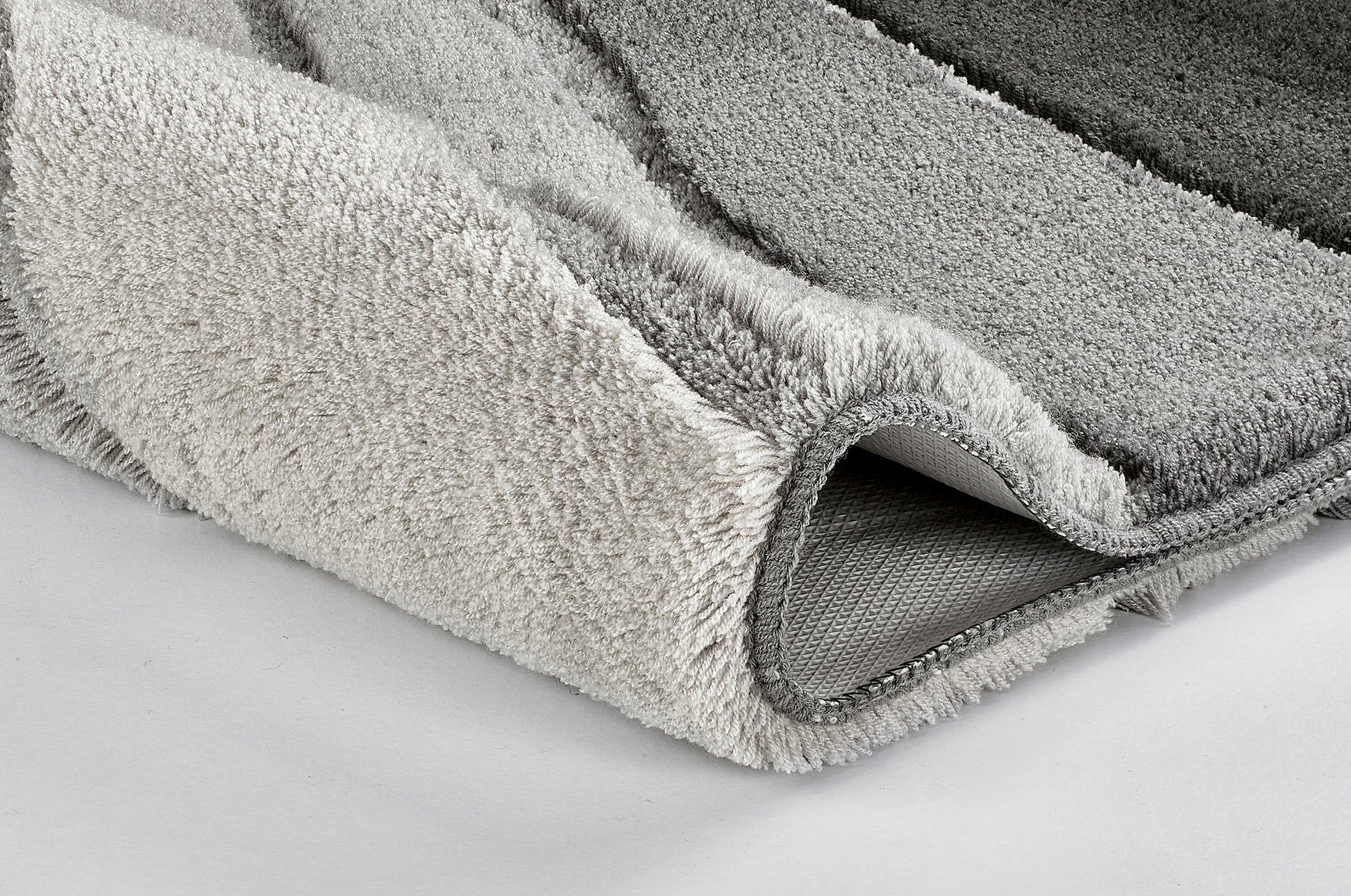 Nahaufnahme einer gefalteten, grau gestreiften Badematte aus Frottier